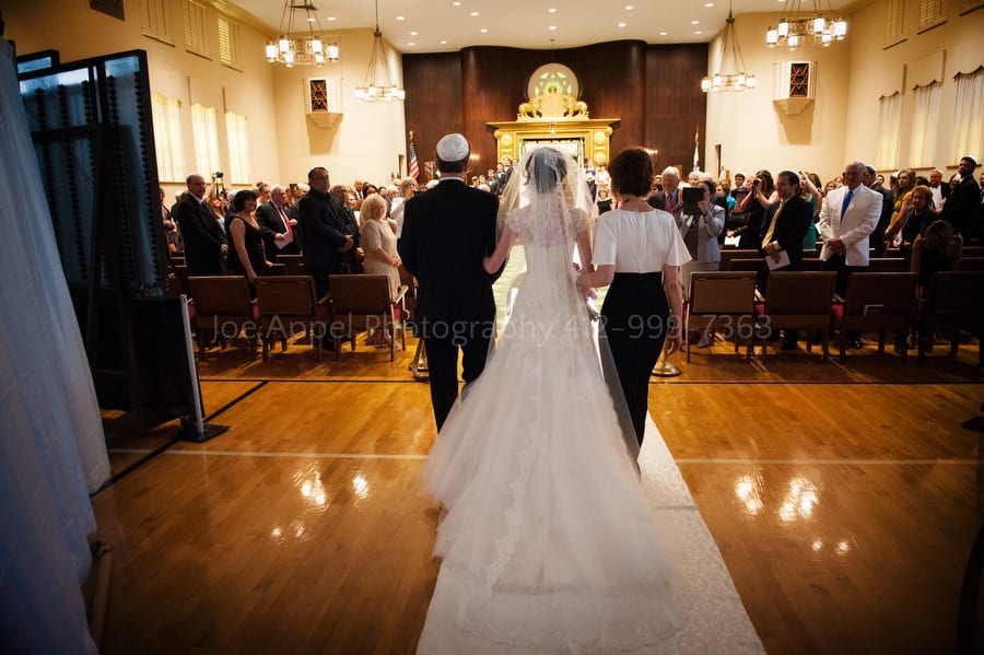 a bride is walked down the aisle at a synagogue by her mother and father during her wedding ceremony West Virginia Wedding Photography