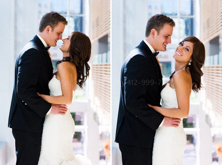 bride and groom stand together on the stairway next to the big windows at fairmont pittsburgh wedding