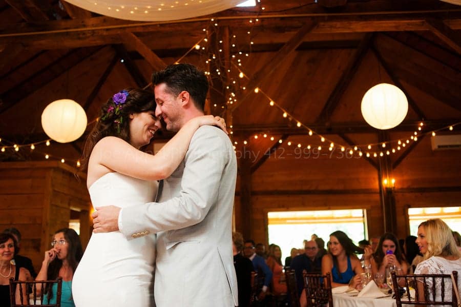 bride and groom share their first dance under strings of lights