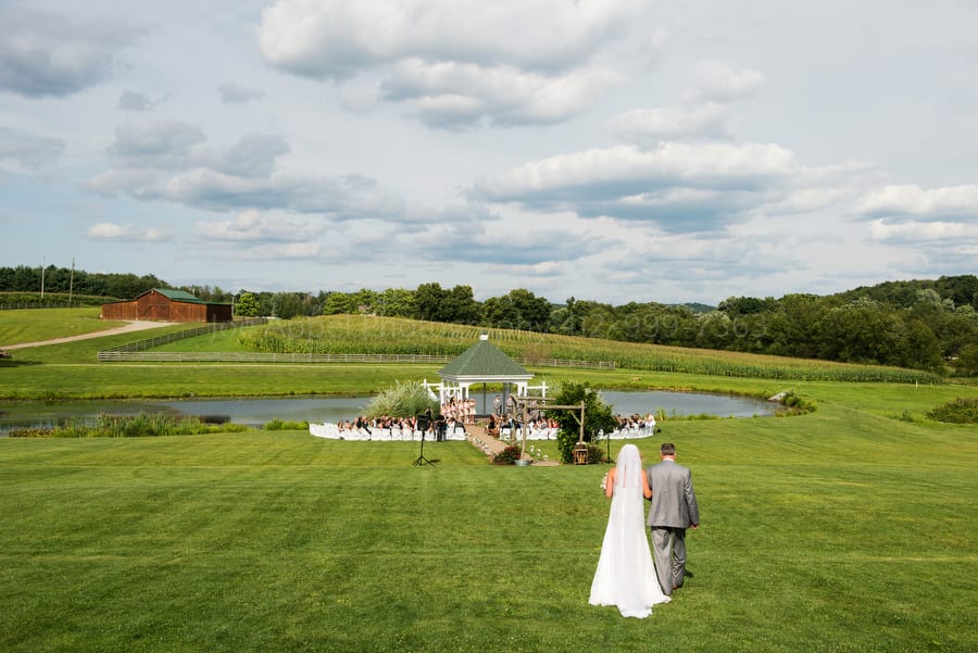 bride and her father walk across a vast lawn on a beautiful summer day on their way to her wedding ceremony