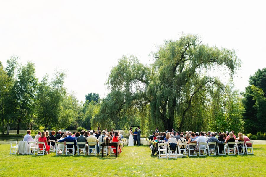 Wide shot of an outdoor wedding taking place beneath a willow tree.