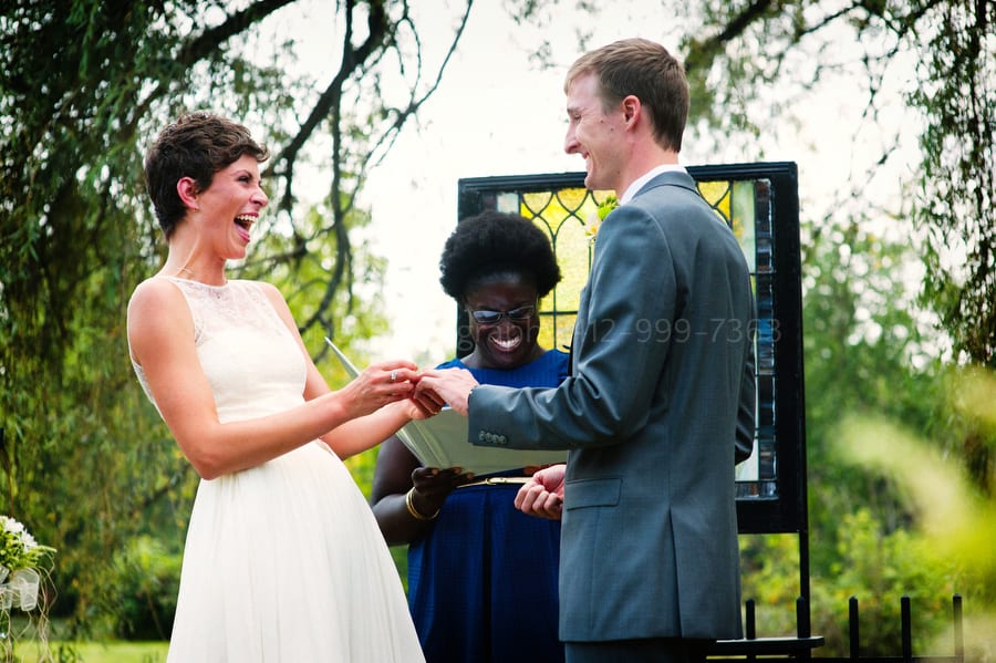A bride laughs as she puts the ring on her groom.