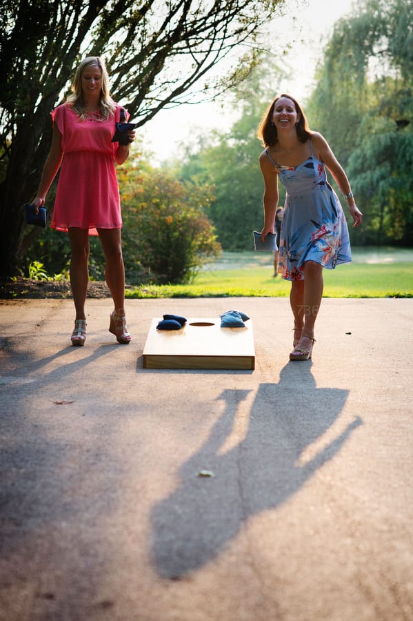 Wedding guests play a game of cornhole as the sun sets behind them.