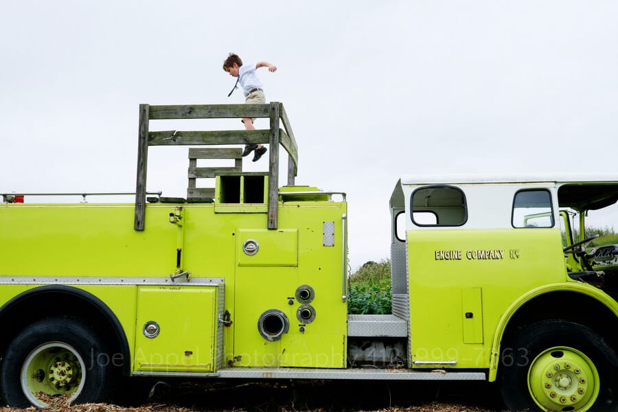 a young boy leaps on top of a fire truck that has been turned into a playground implement outdoor wedding in pittsburgh