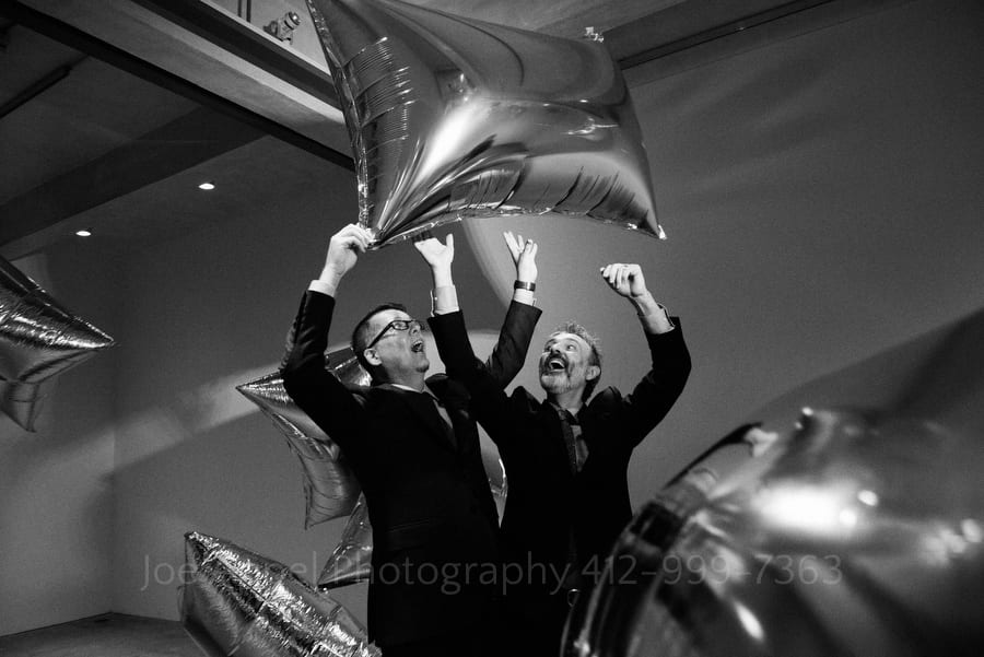 two men play with a silver mylar pillow after their andy warhol museum wedding