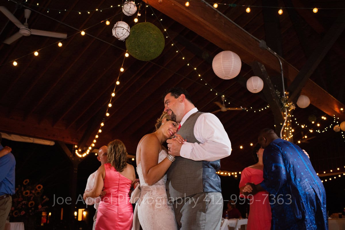 Bride and groom embrace as they dance together at their wedding reception.