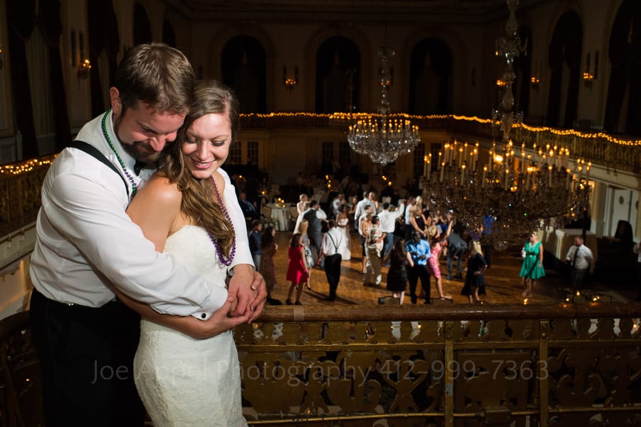 A groom embraces his bride as they look over the dance floor at their Omni William Penn wedding.