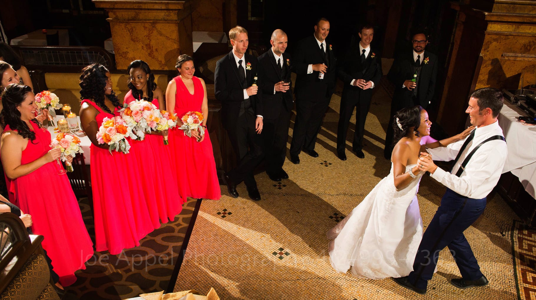 Seen from above, a bride and groom share their first dance in front of their bridal party.