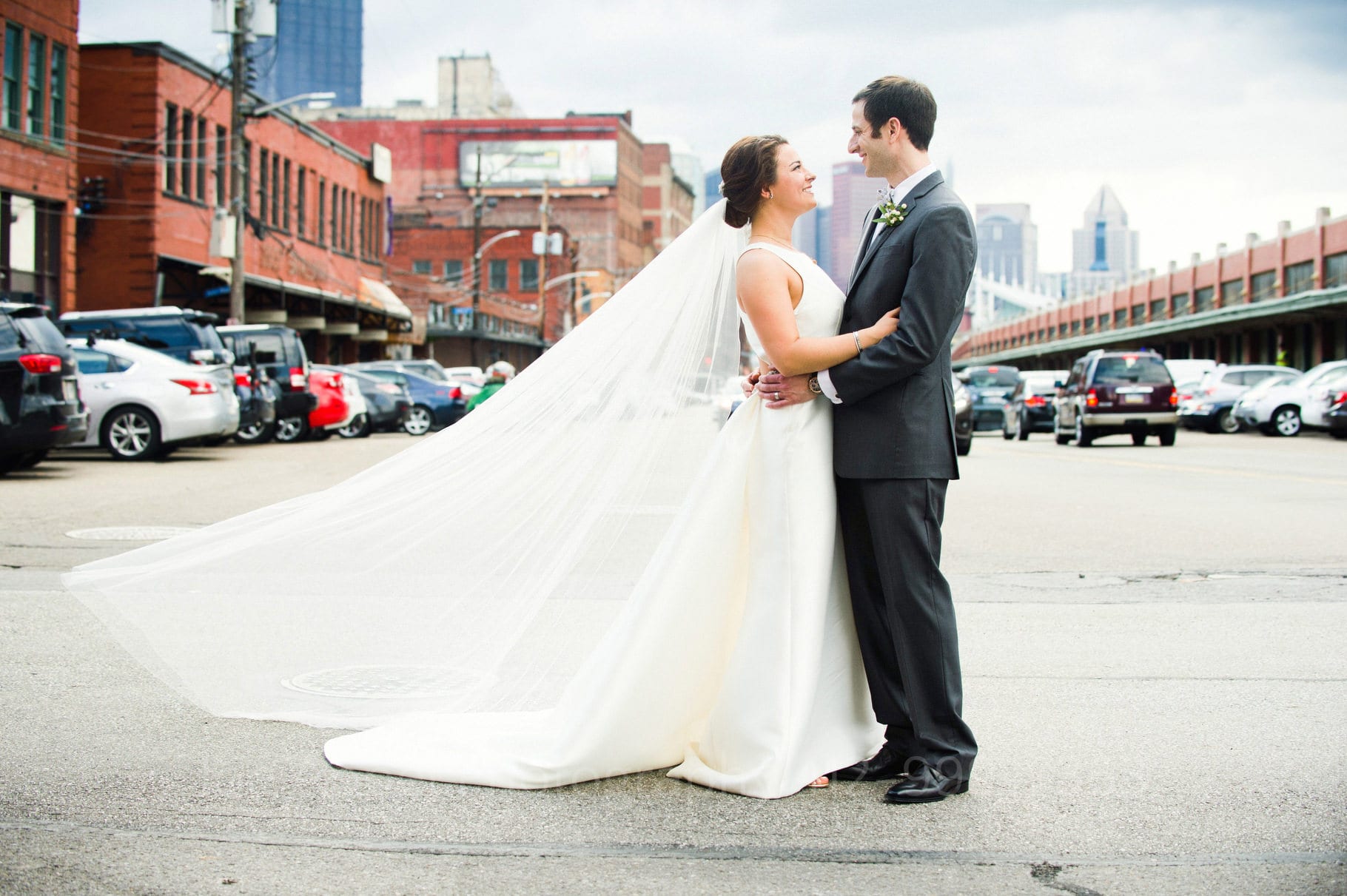 A bride's veil blows in the wind behind her as she faces her husband while they stand on Smallman Street in the Strip District in Pittsburgh near St. Stanislaus (St. Stan's).