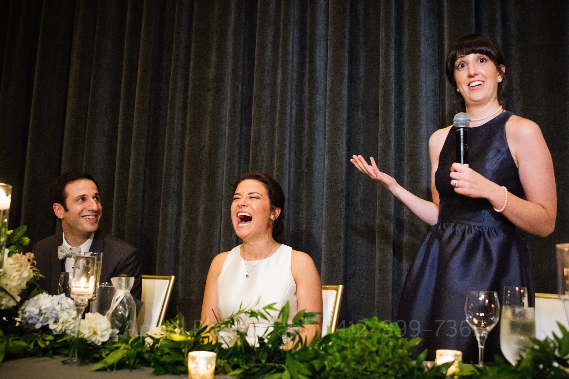 Bride and groom laugh as the maid of honor delivers her speech at a Hotel Monaco wedding.
