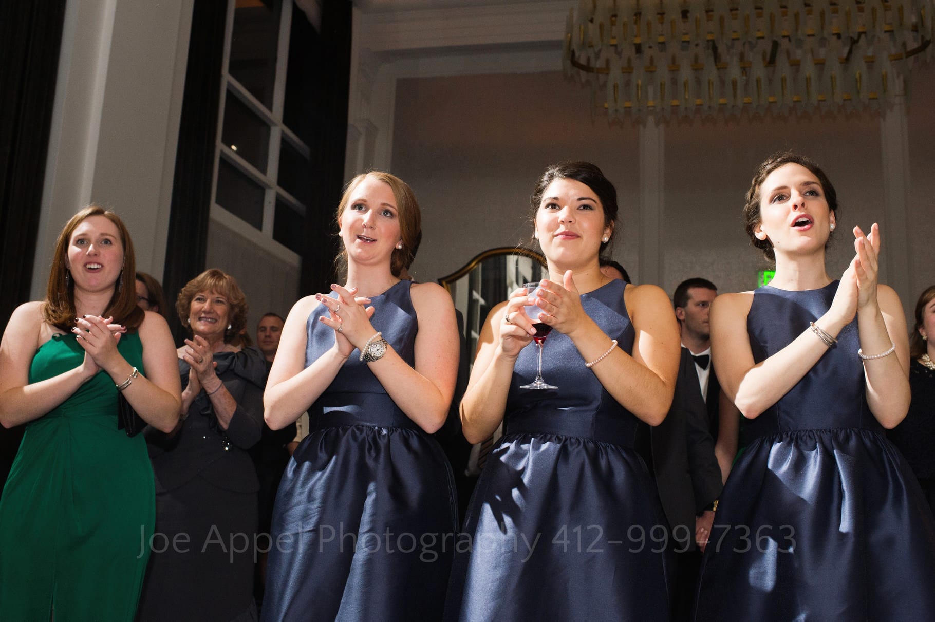 Bridesmaids smile, tear up, and clap their hands while watching the bride dance with her dad at the Hotel Monaco.