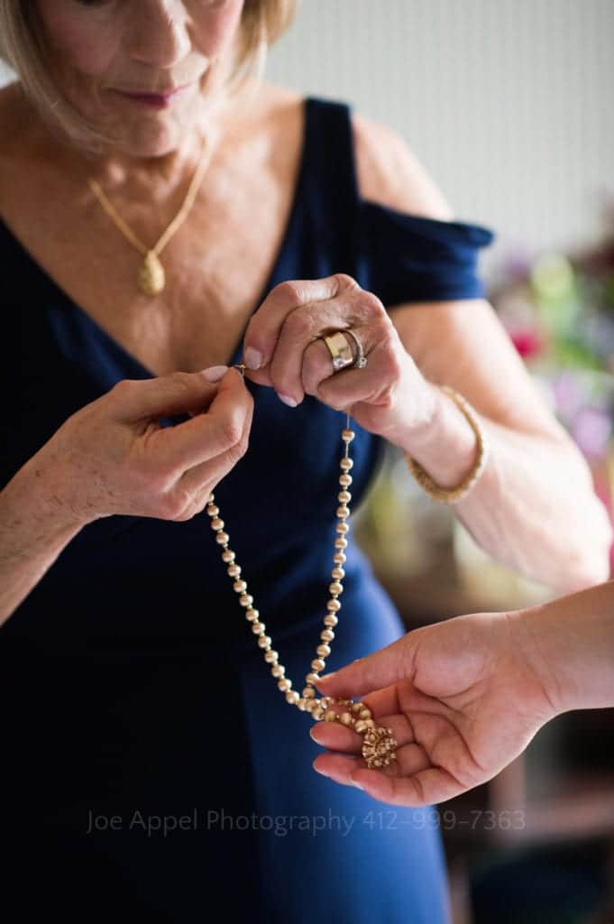closeup of a woman's hands opening the clasp on a pearl necklace