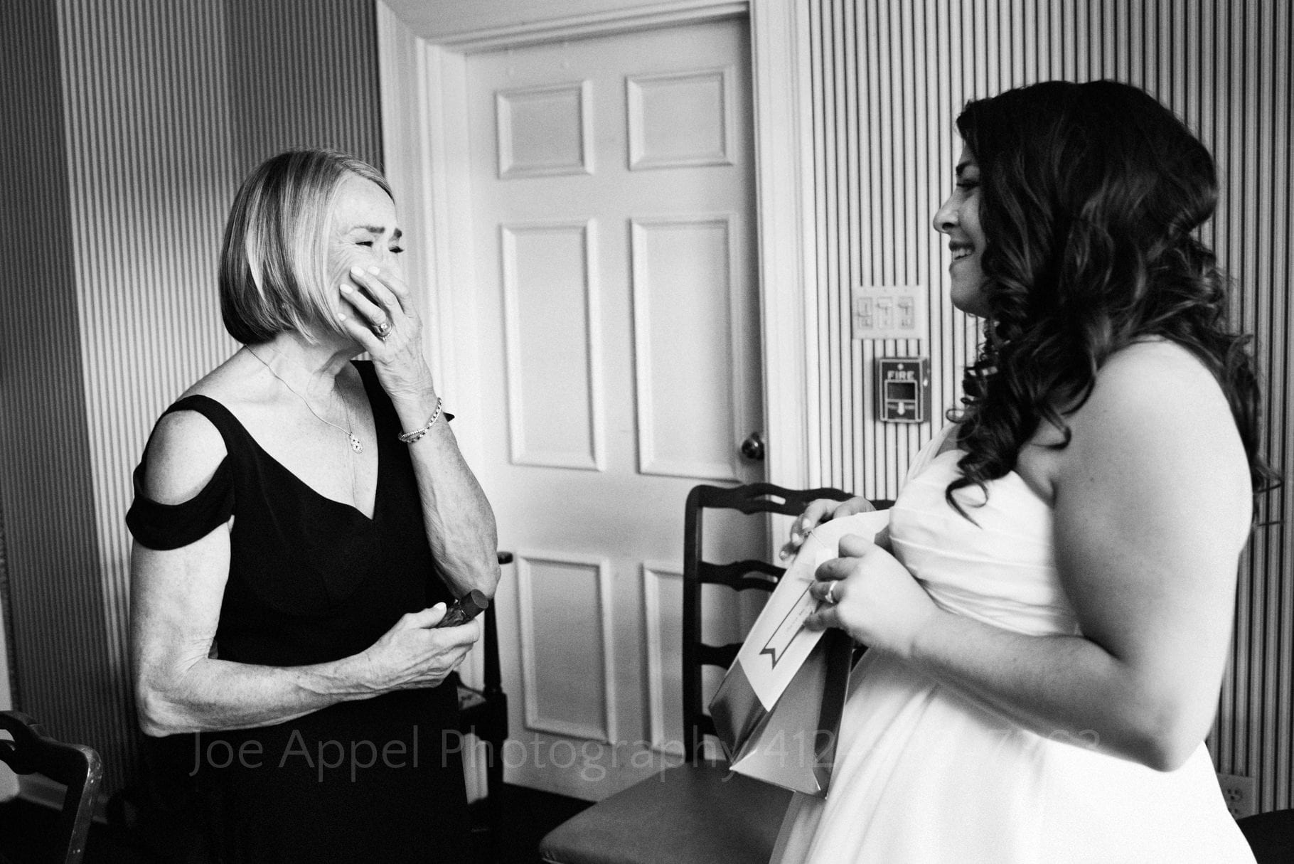 A mother and daughter face each other as the mother holds back tears on her daughter's wedding day
