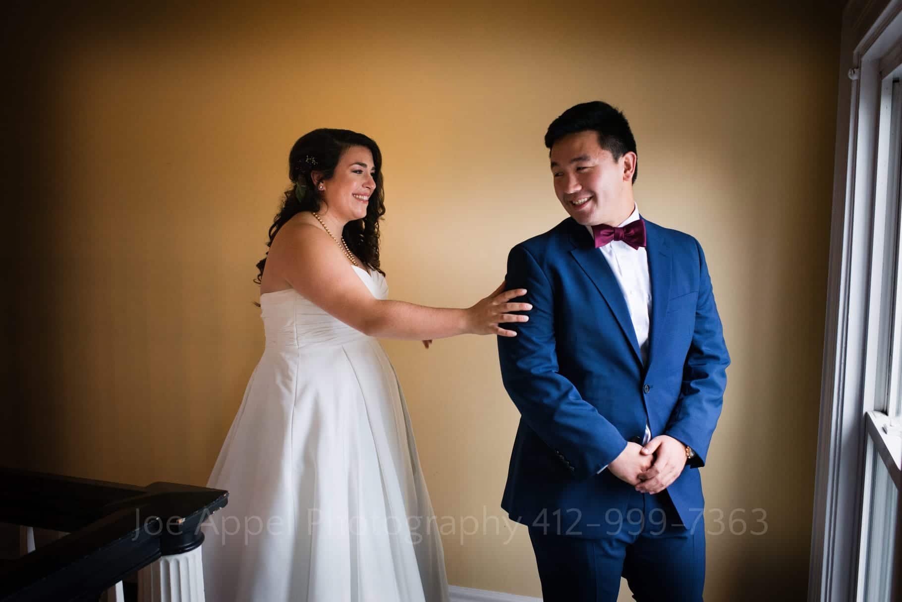 a groom smiles as he turns to see his bride as she puts her hand on his arm during their first look at their Pittsburgh Golf Club Wedding