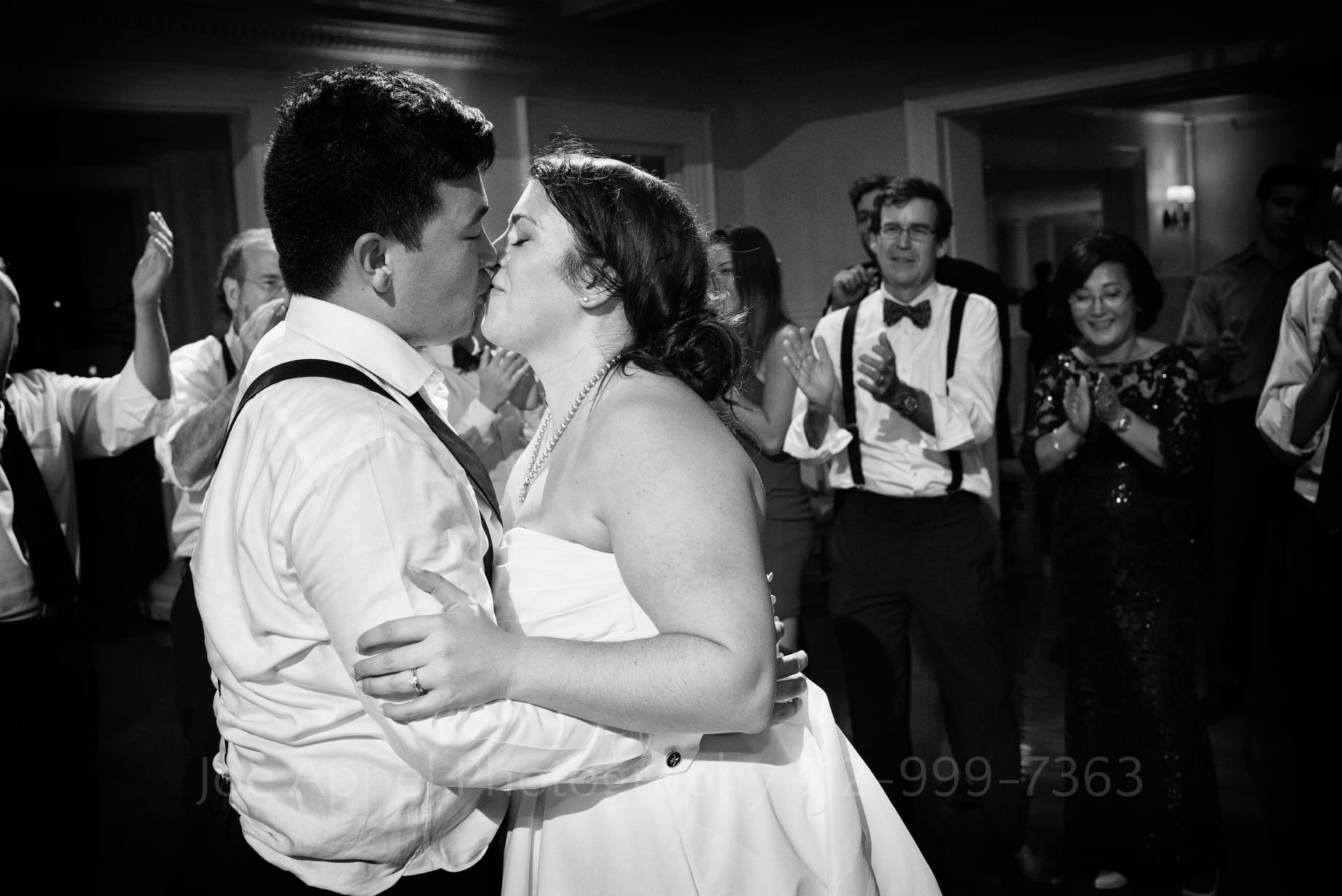 Bride and groom kiss on the dance floor as their guests applaud during their Pittsburgh Golf Club Wedding.