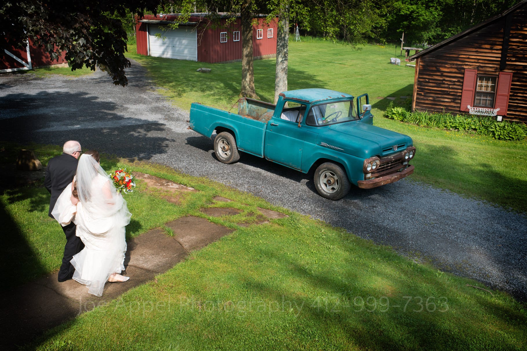 a bride and her father walk along a path towards an old rusty Ford pickup truck during their Chanteclaire Farm Wedding.