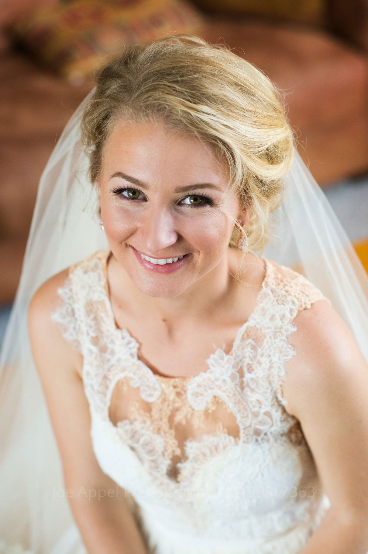Closeup portrait of a blonde bride in a lacy dress with a veil.