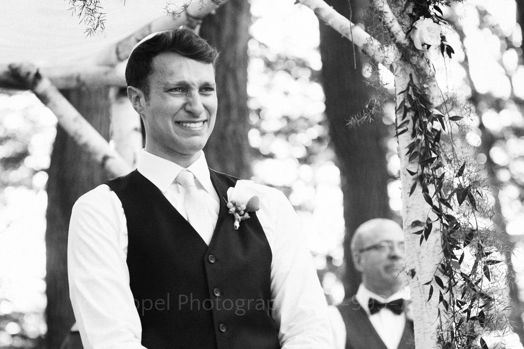 A groom is overcome with emotion as he sees his bride walking towards him.