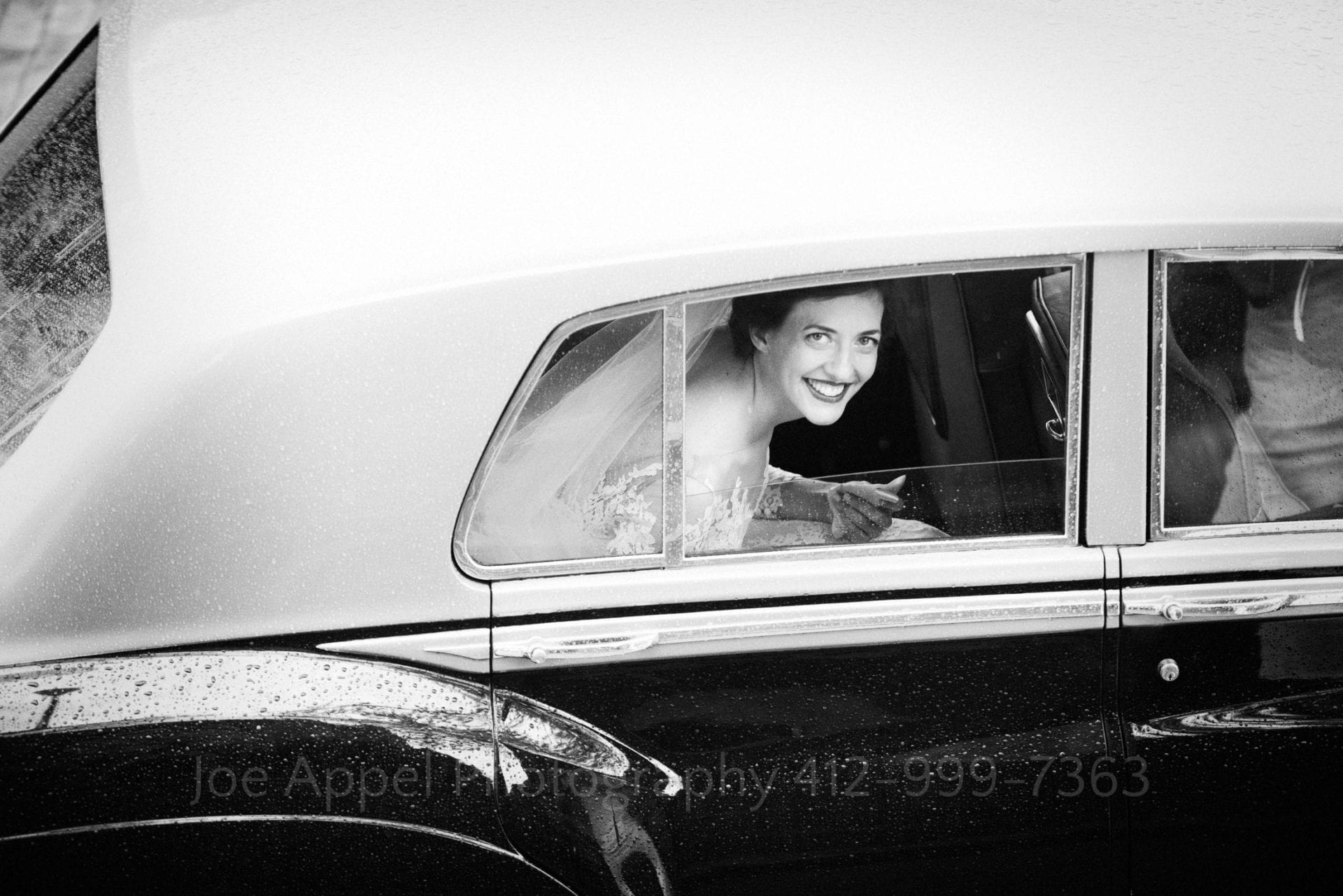A bride looks up from the back passengers side window of an antique Bentley that delivered her to the church.