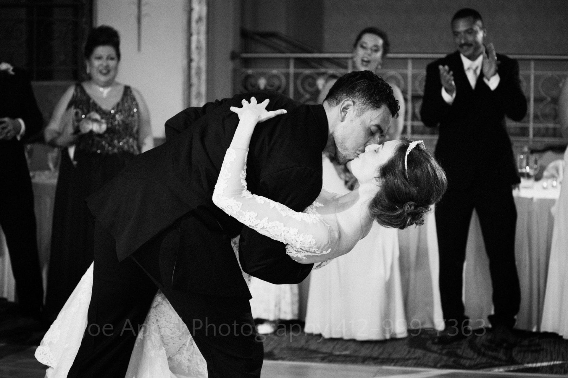 Groom dips his bride and kisses her at the end of their first dance at their William Penn Hotel Wedding.