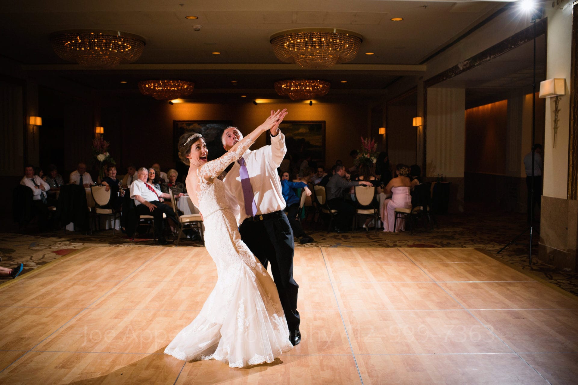 Father and daughter dance with a dramatic and humorous gesture looking skyward with their arms outstretched.