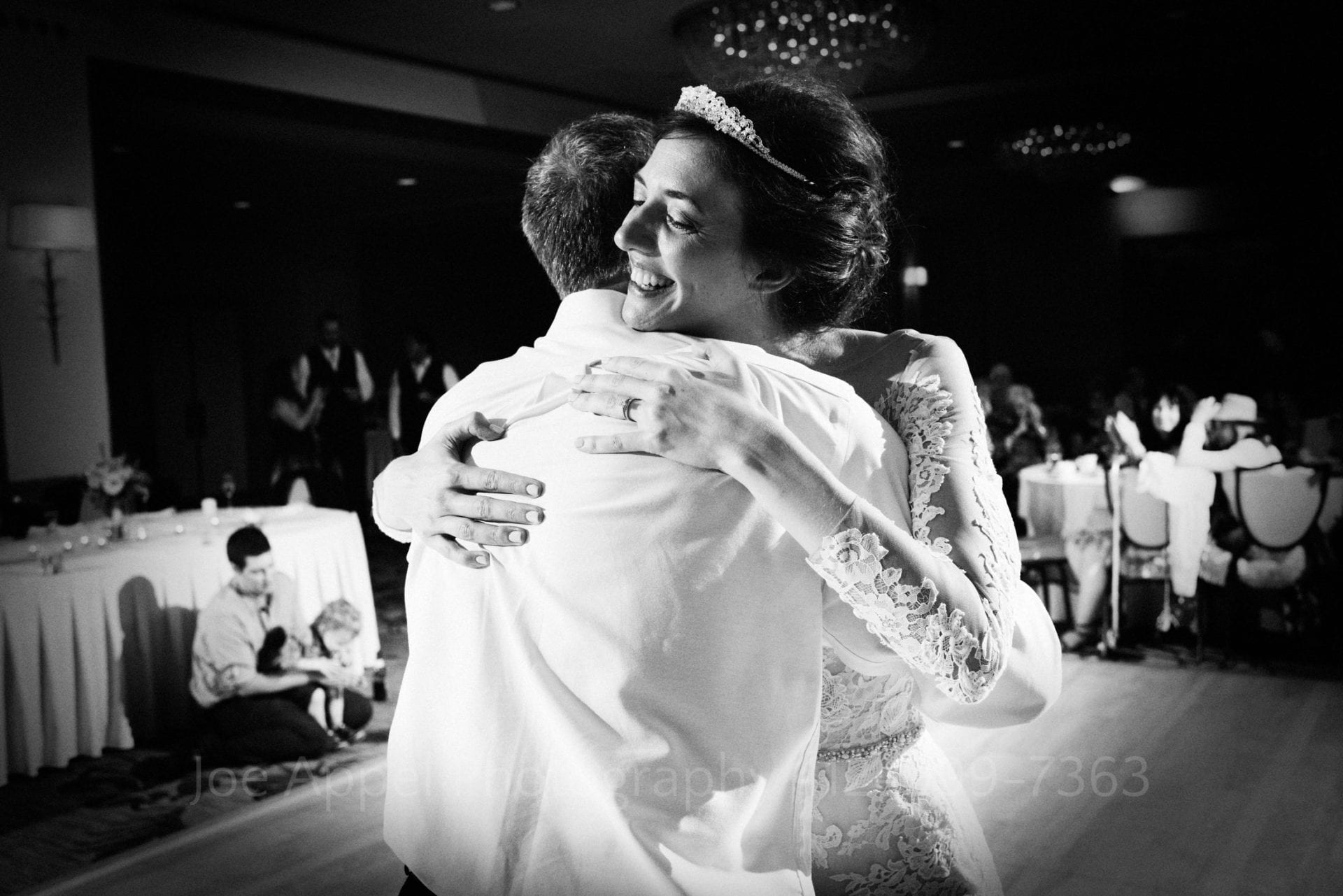 Bride smiles as she embraces her father at the conclusion of their dance.
