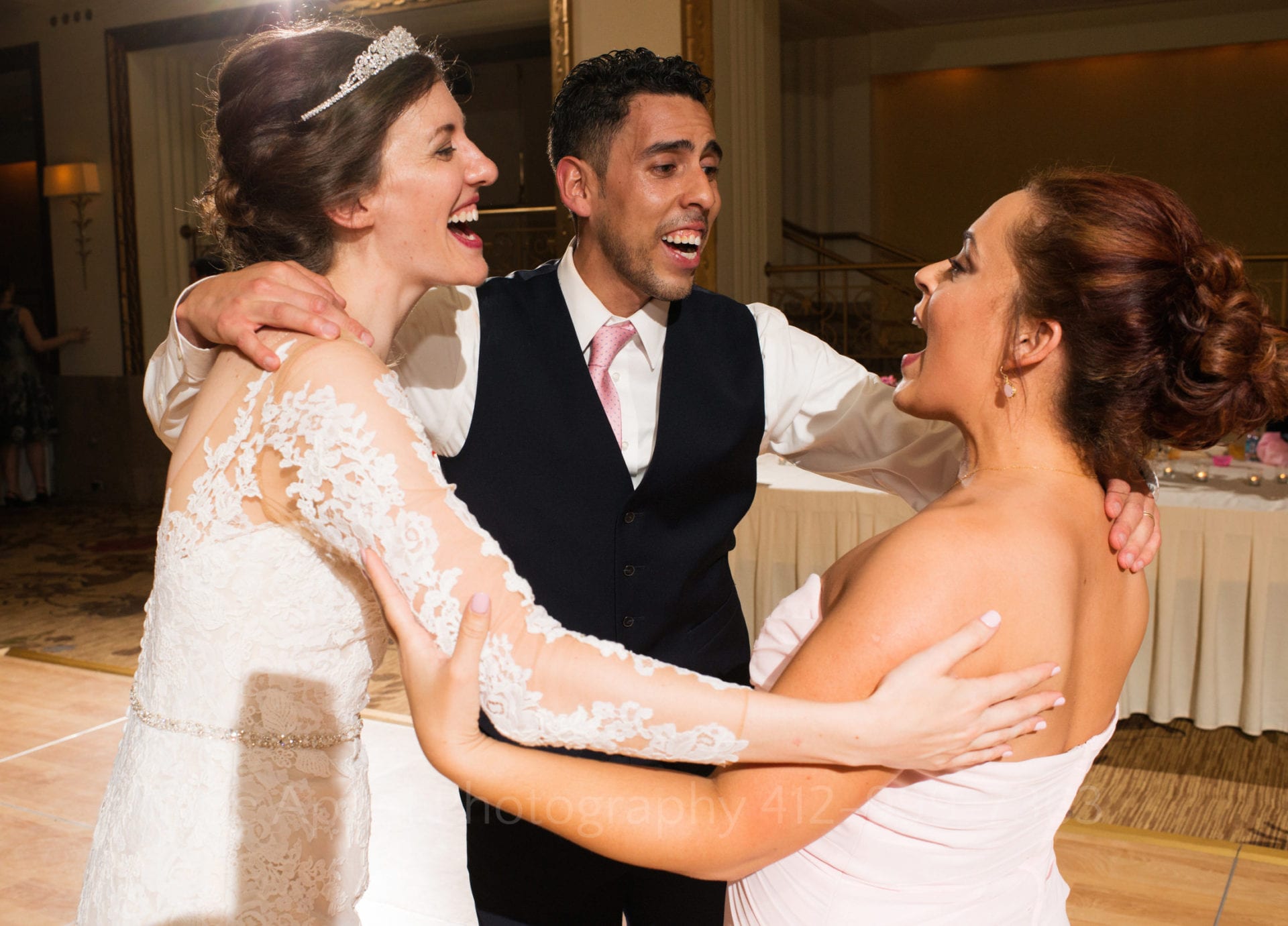 Bride and groom link arms as they dance with the groom's sister during the reception of their William Penn Hotel Wedding.