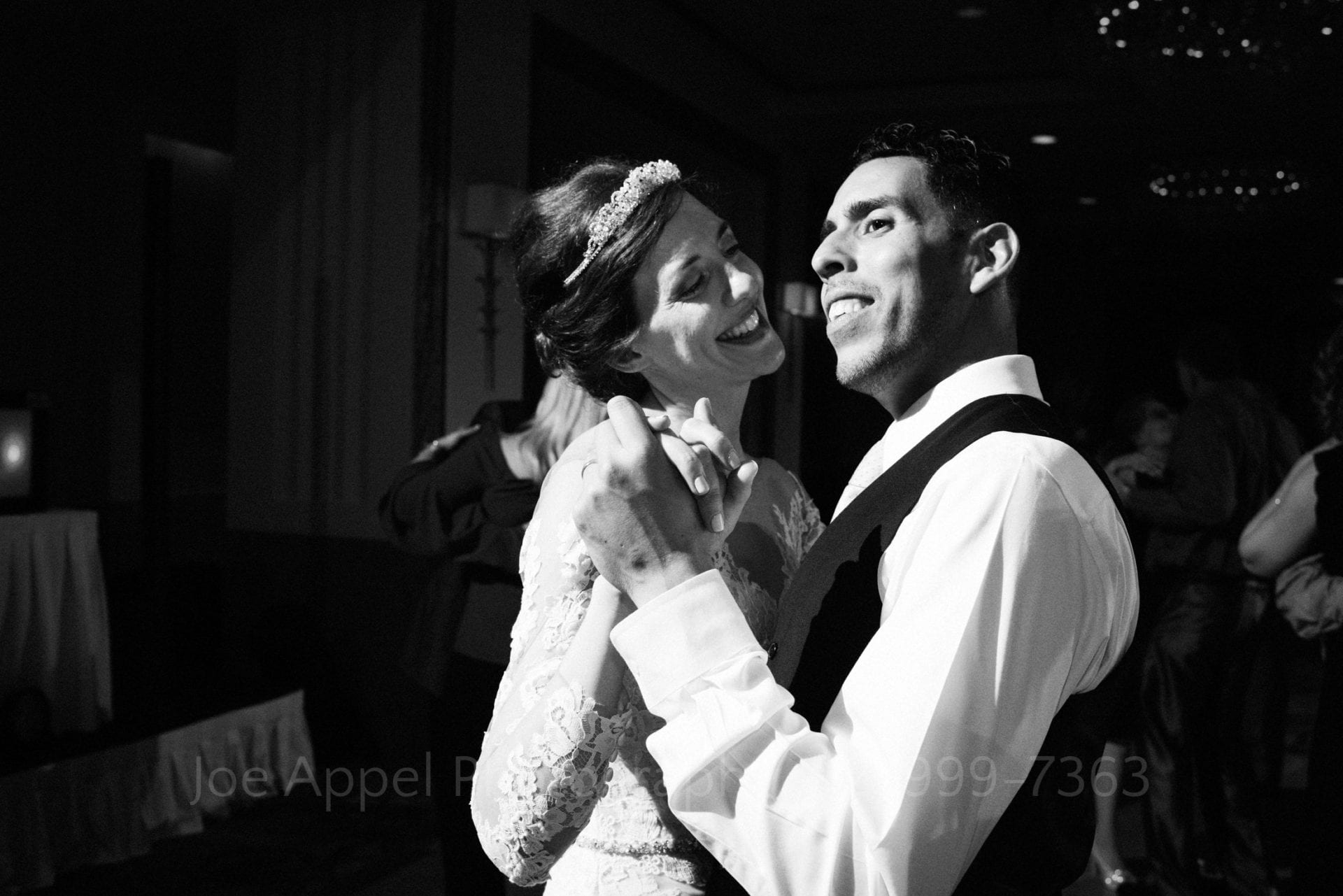 Black and white photo of a smiling bride and groom as they dance during their William Penn Hotel Wedding.