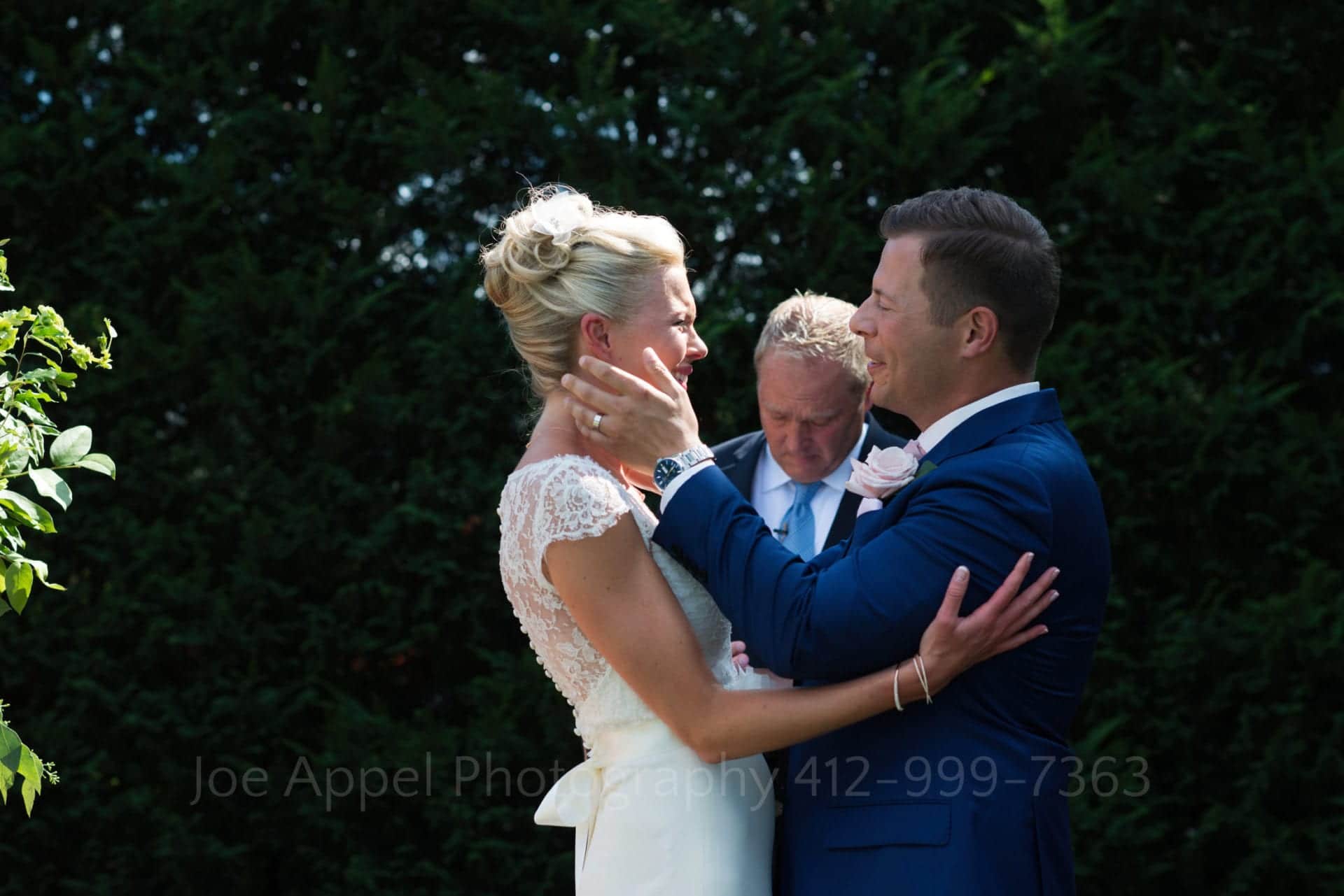 A groom holds his bride's face as they prepare to kiss near the end of their wedding ceremony during their Omni Bedford Springs Resort Wedding.