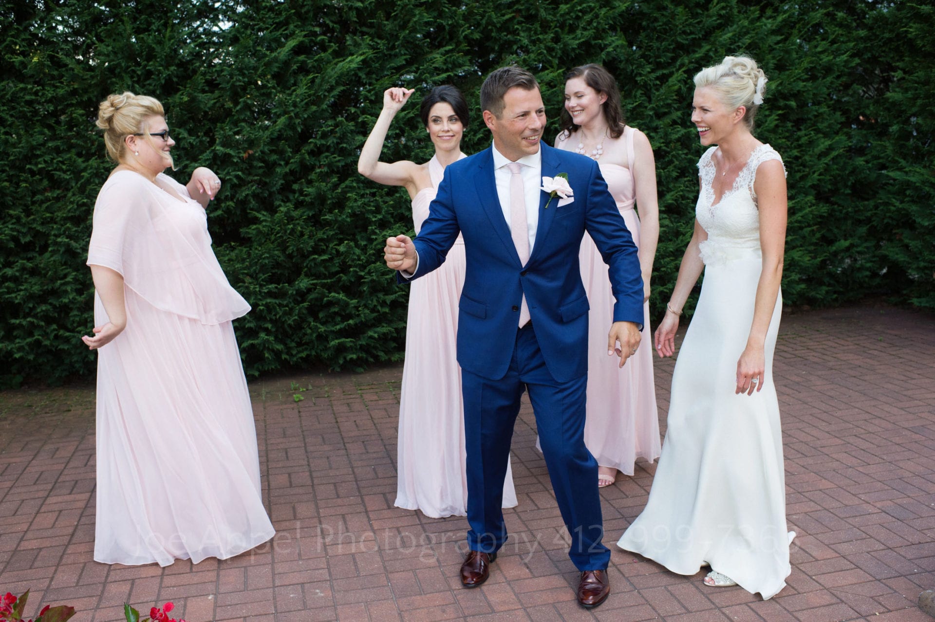 A groom shows off his dance moves as he stands in front of his bride and her bridesmaids during their Omni Bedford Springs Resort Wedding. The bride stands at right laughing.