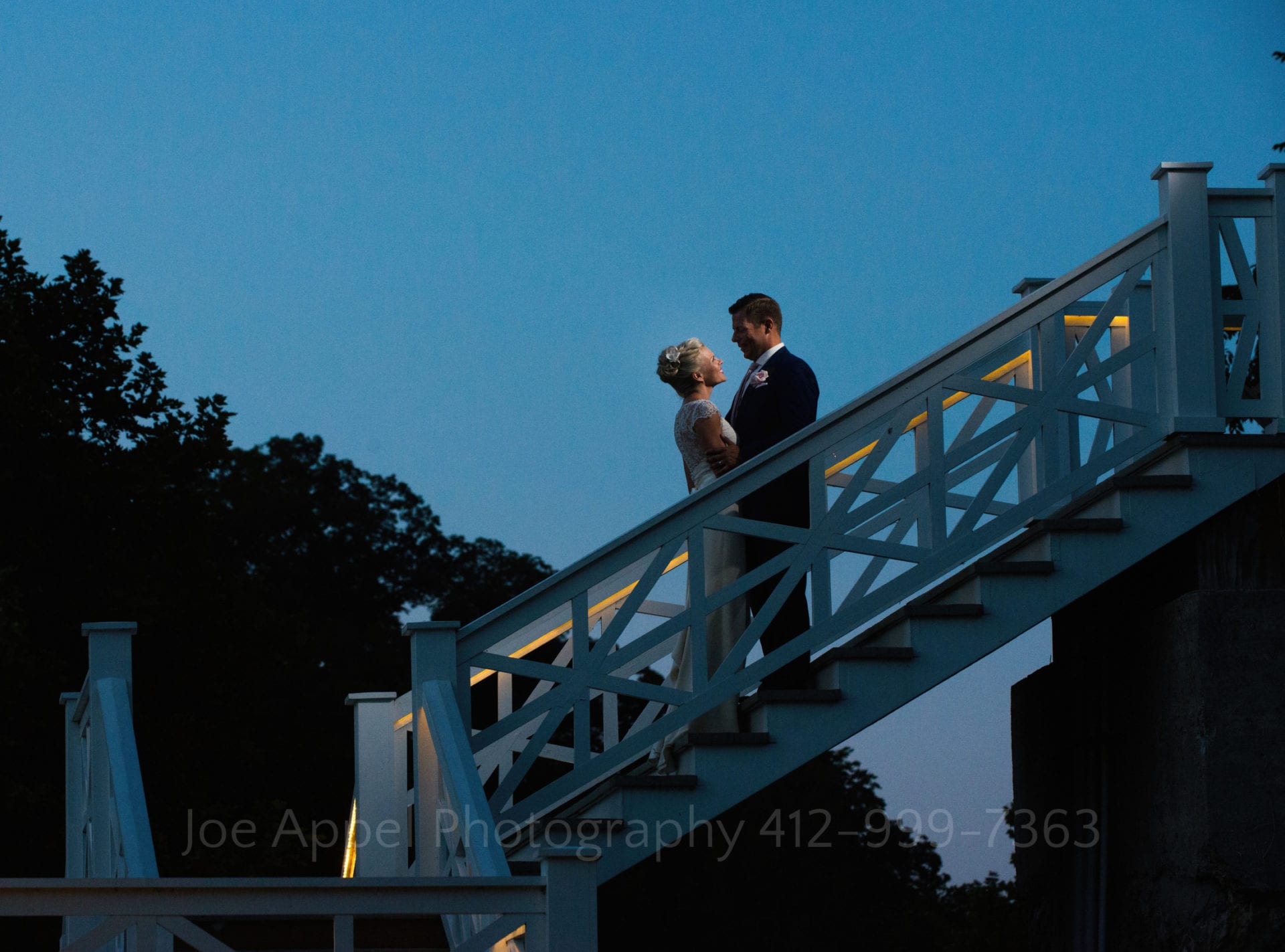 A bride and groom stand on an outdoor stairway beneath deep blue twilight skies during their Omni Bedford Springs Resort Wedding.