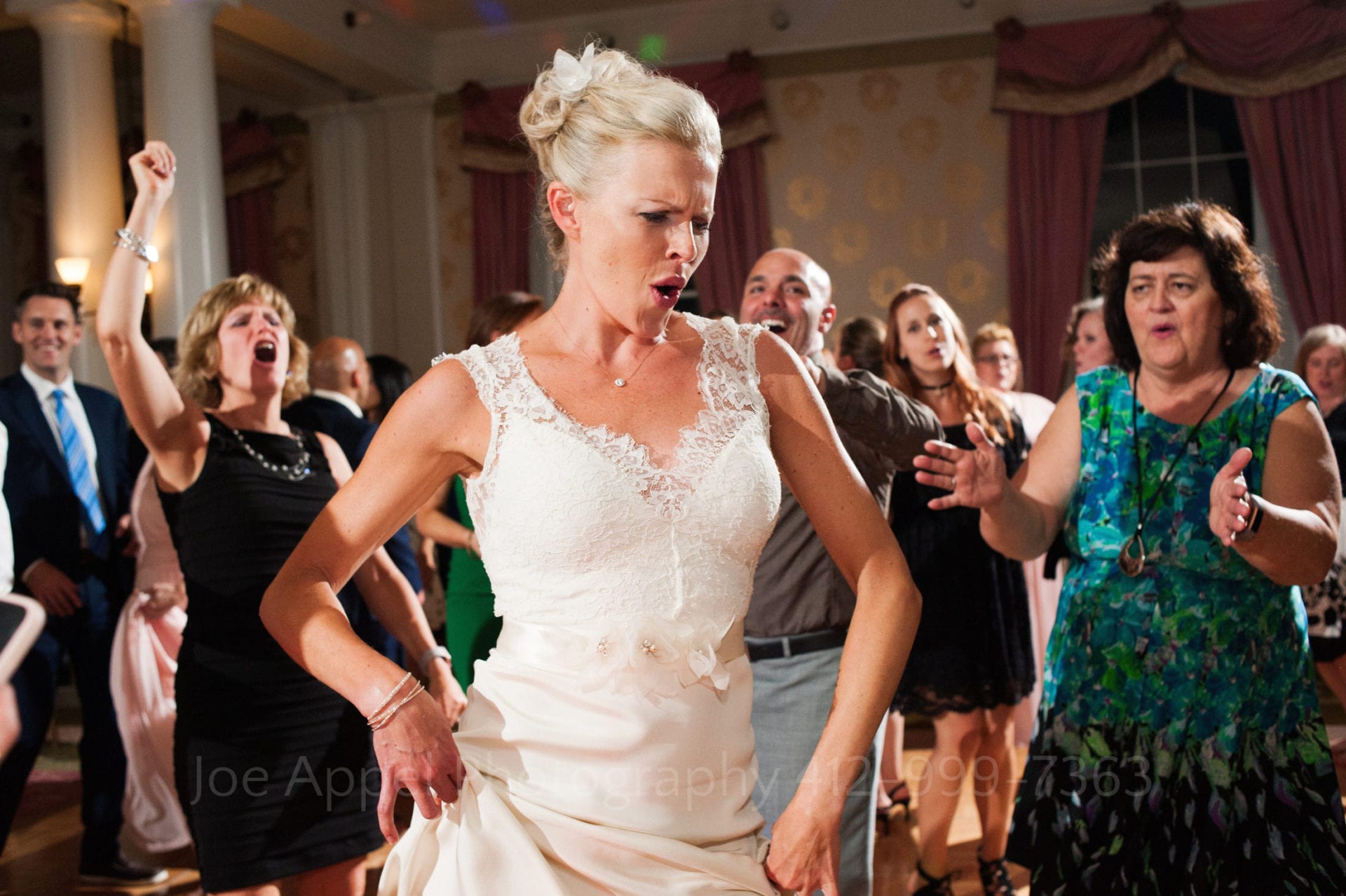 A bride hitches up her dress at her hips as she dances in front of her cheering guests during their Omni Bedford Springs Resort Wedding.