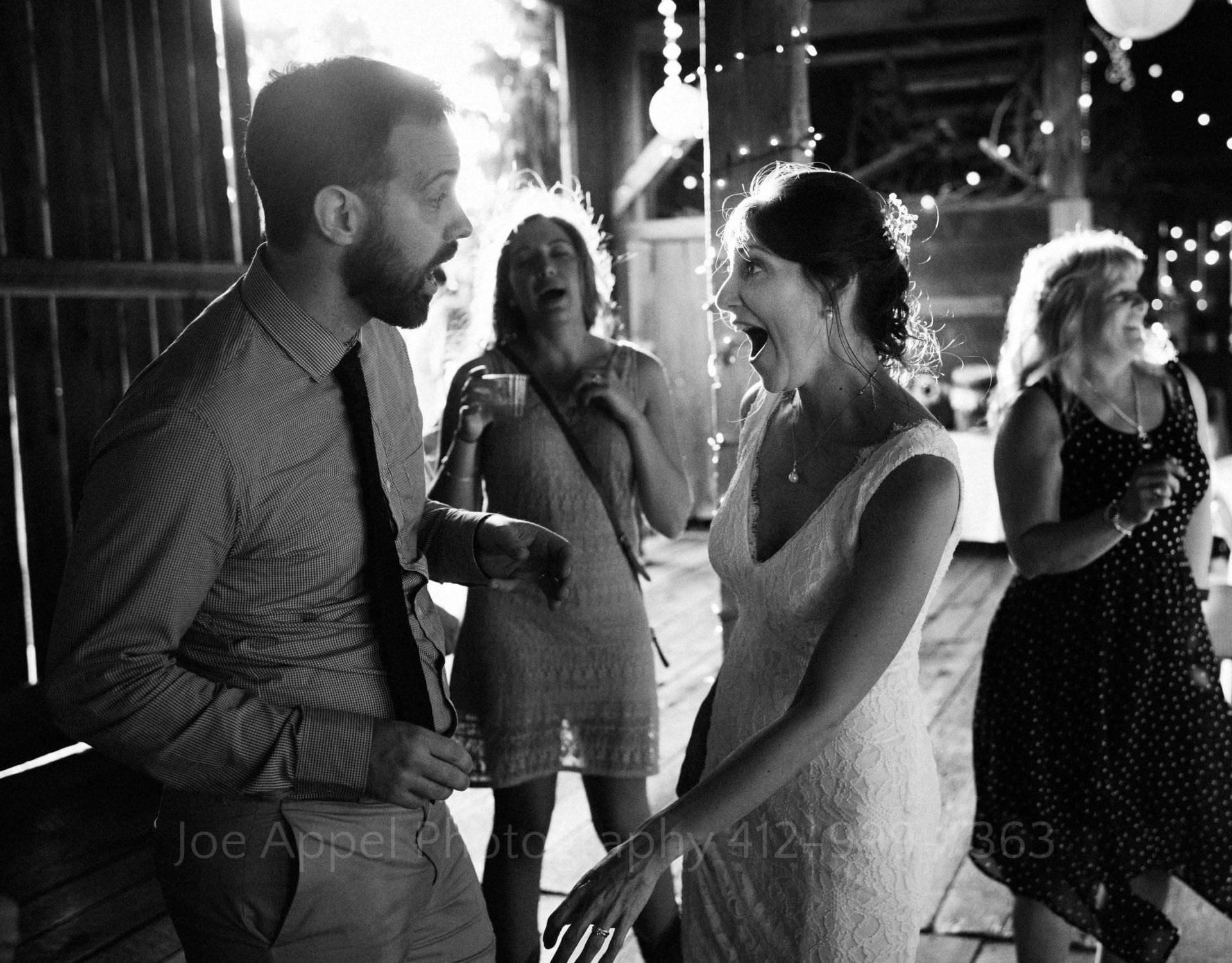 Bride and groom dance together in a barn as sun streams through the open door.