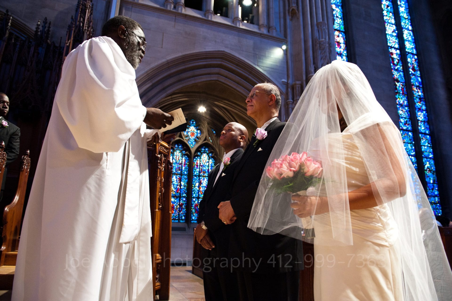 An african american pastor faces a father standing between his daughter and son in law to be at heinz memorial chapel