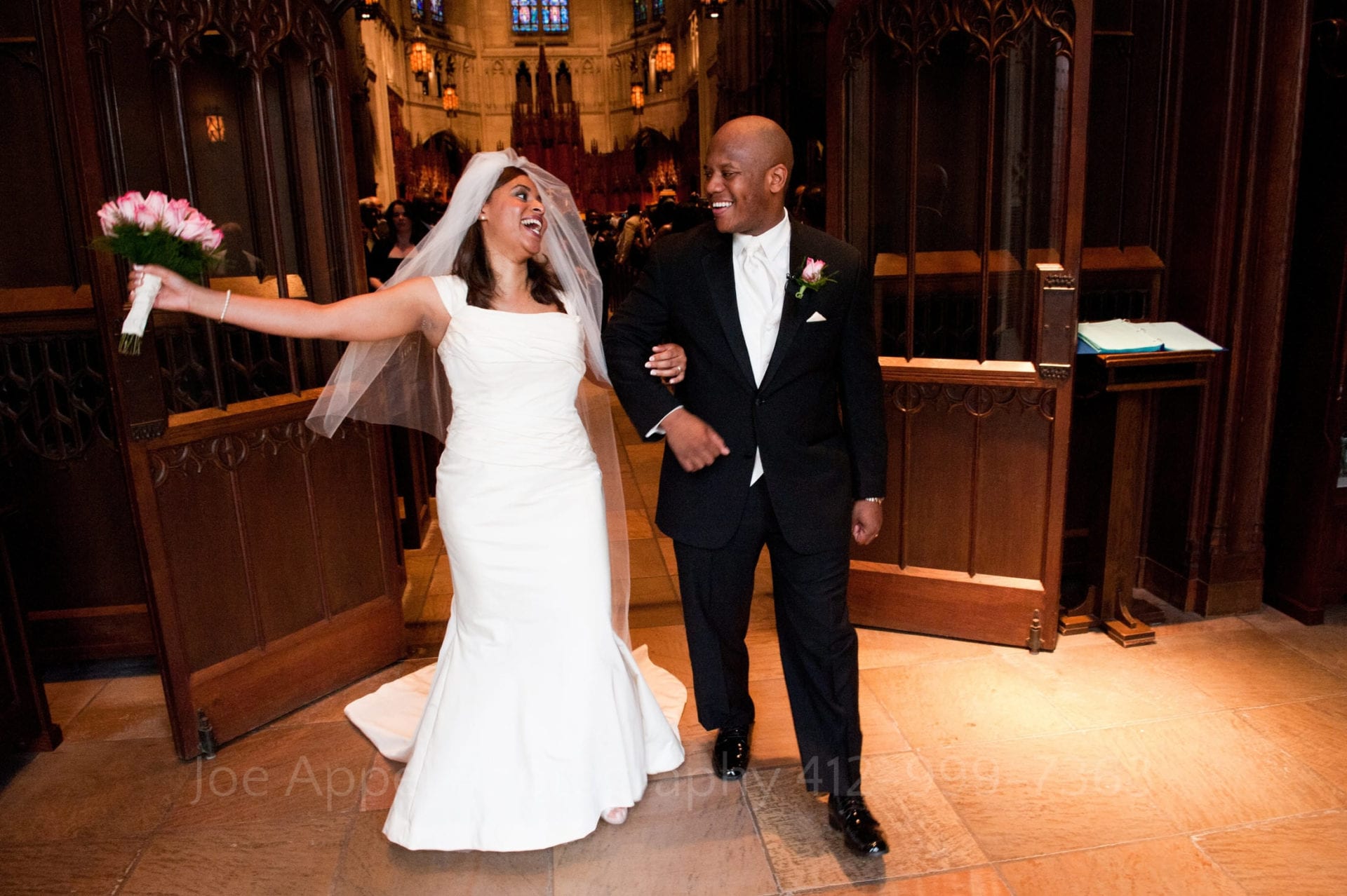 a bride holds her hand out and laughs as she and her groom walk out of the back of heinz memorial chapel.