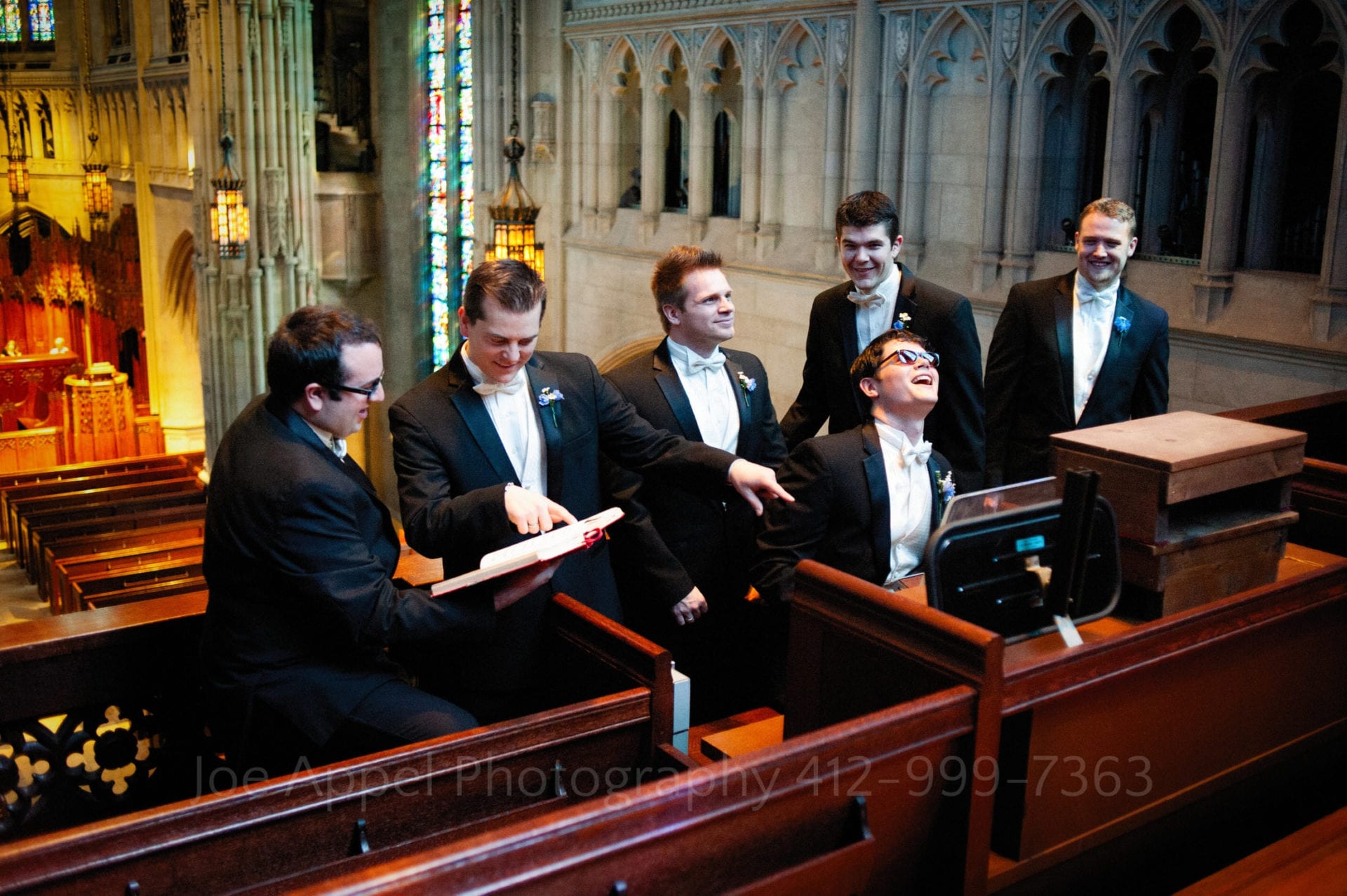 A groom wears sunglasses as he pretends to play the organ in the loft at Heinz memorial chapel while surrounded by his groomsmen.