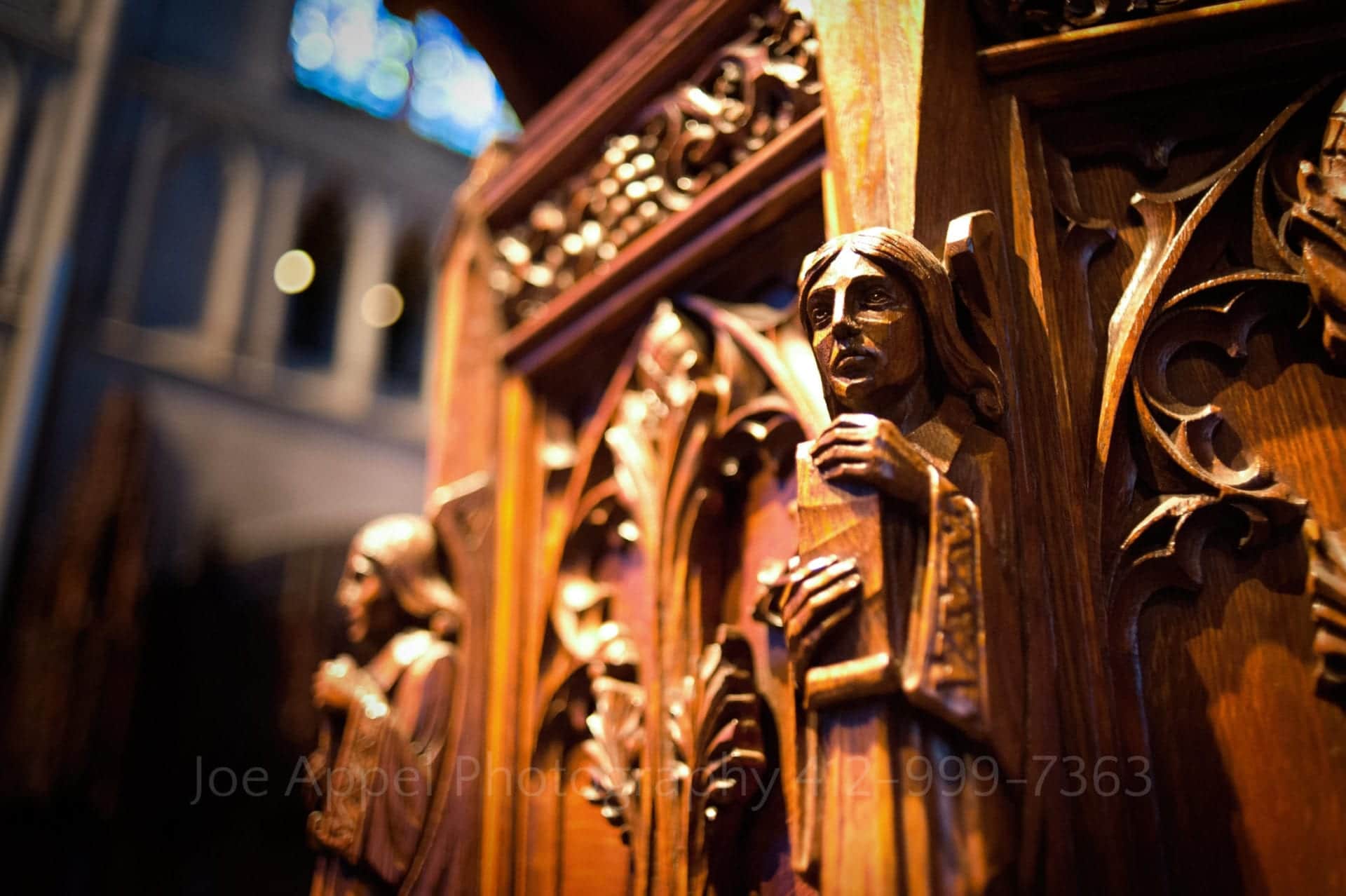 a carved wooden saint holds a book in a detail photo of the altar at heinz memorial chapel.