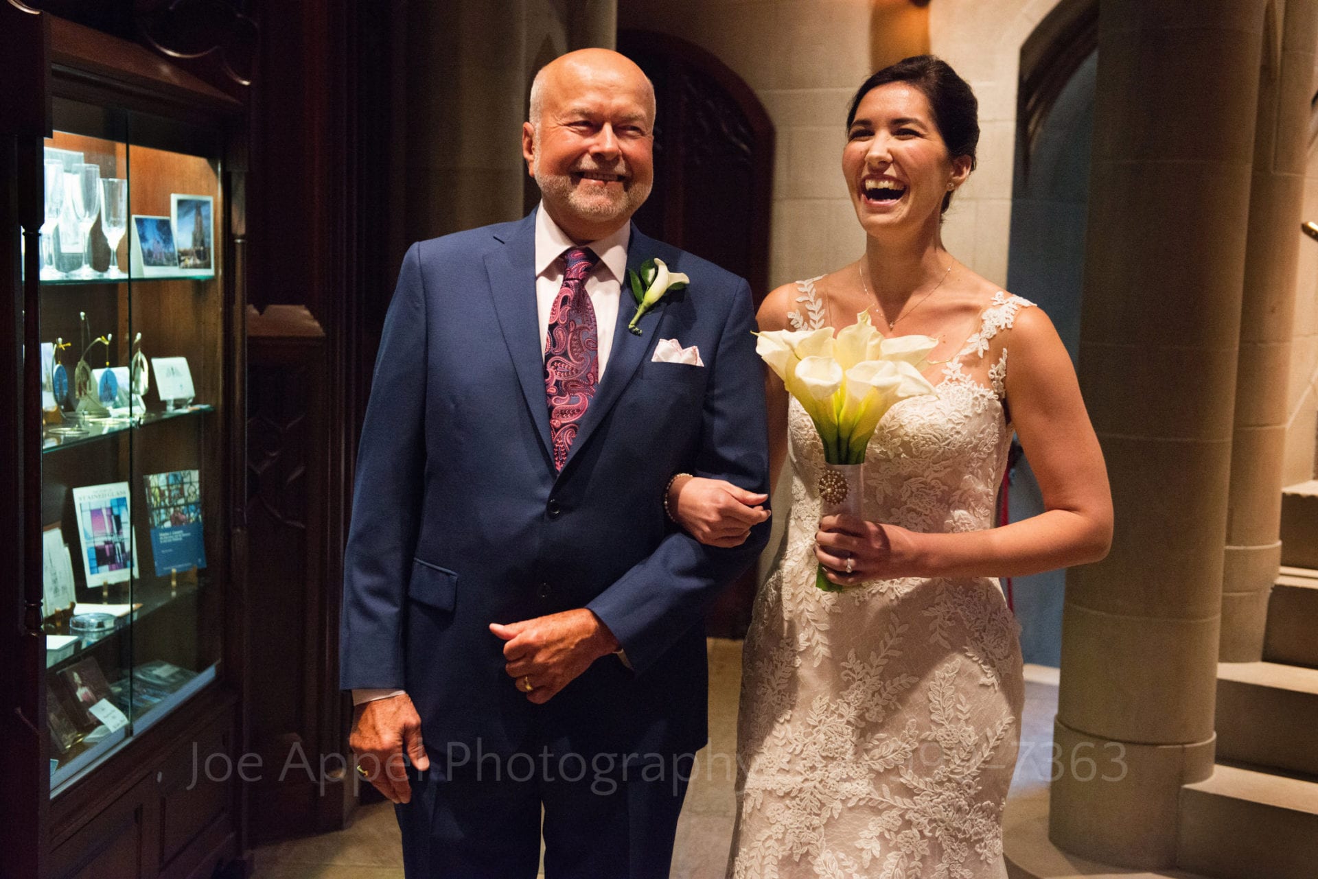 A bride holds her bouquet as she has her arm around her father's arm as they laugh during her Heinz Chapel and LeMont Wedding.