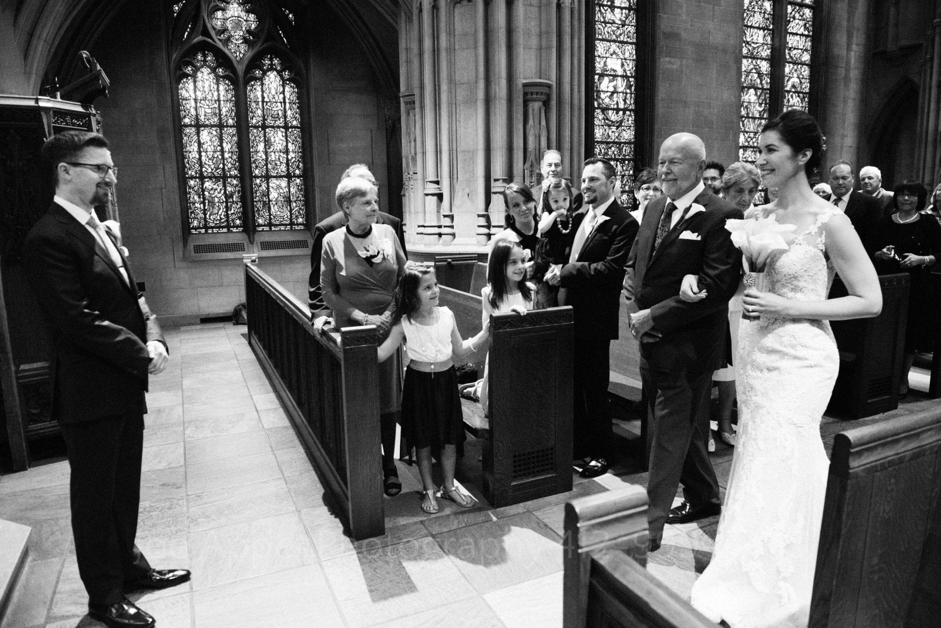 A bride and her father walk towards the groom who smiles at left near the altar during their Heinz Chapel and LeMont Wedding.
