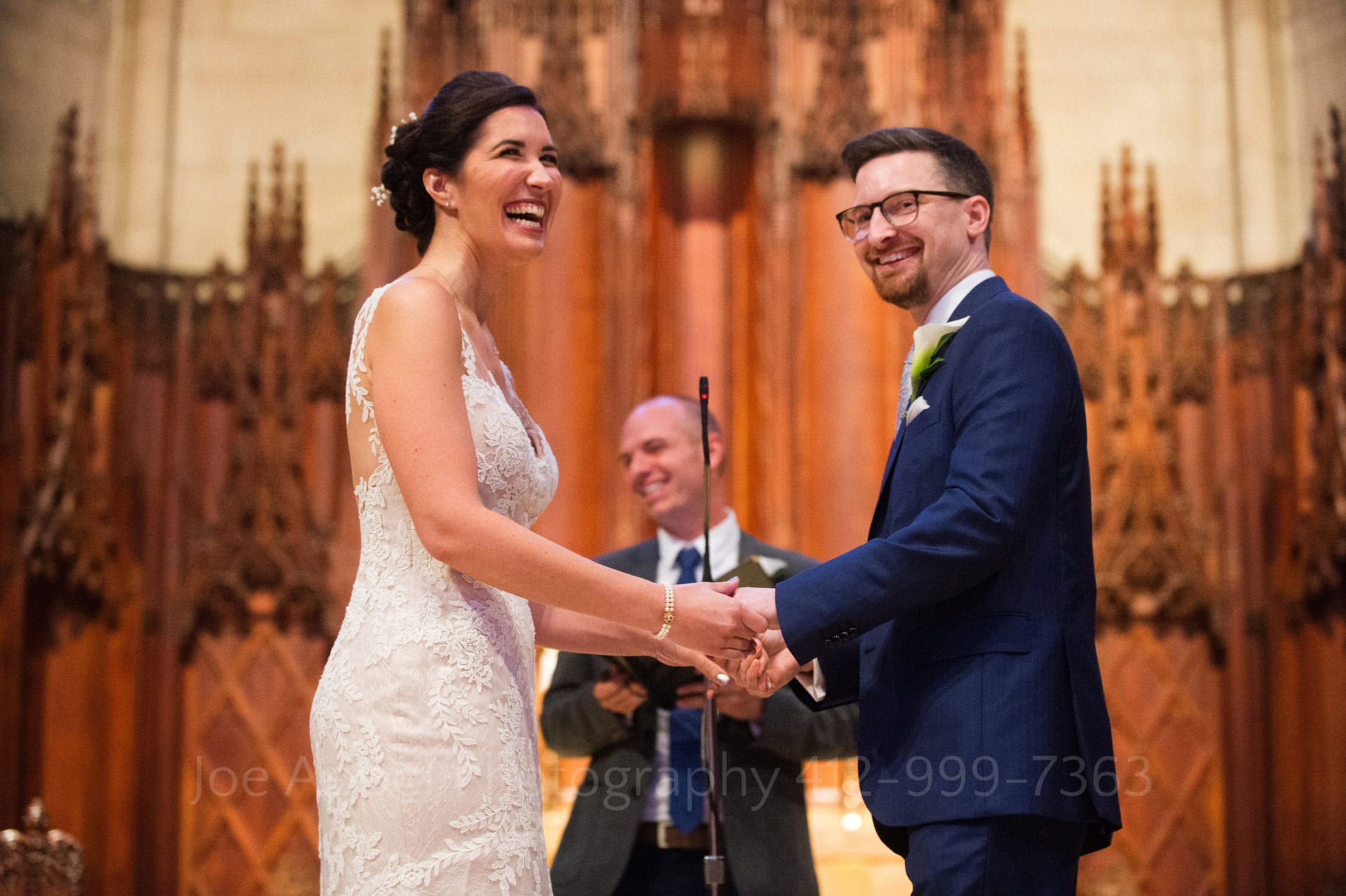 A bride and groom laugh as they hold hands and exchange wedding vows during their Heinz Chapel and LeMont Wedding.