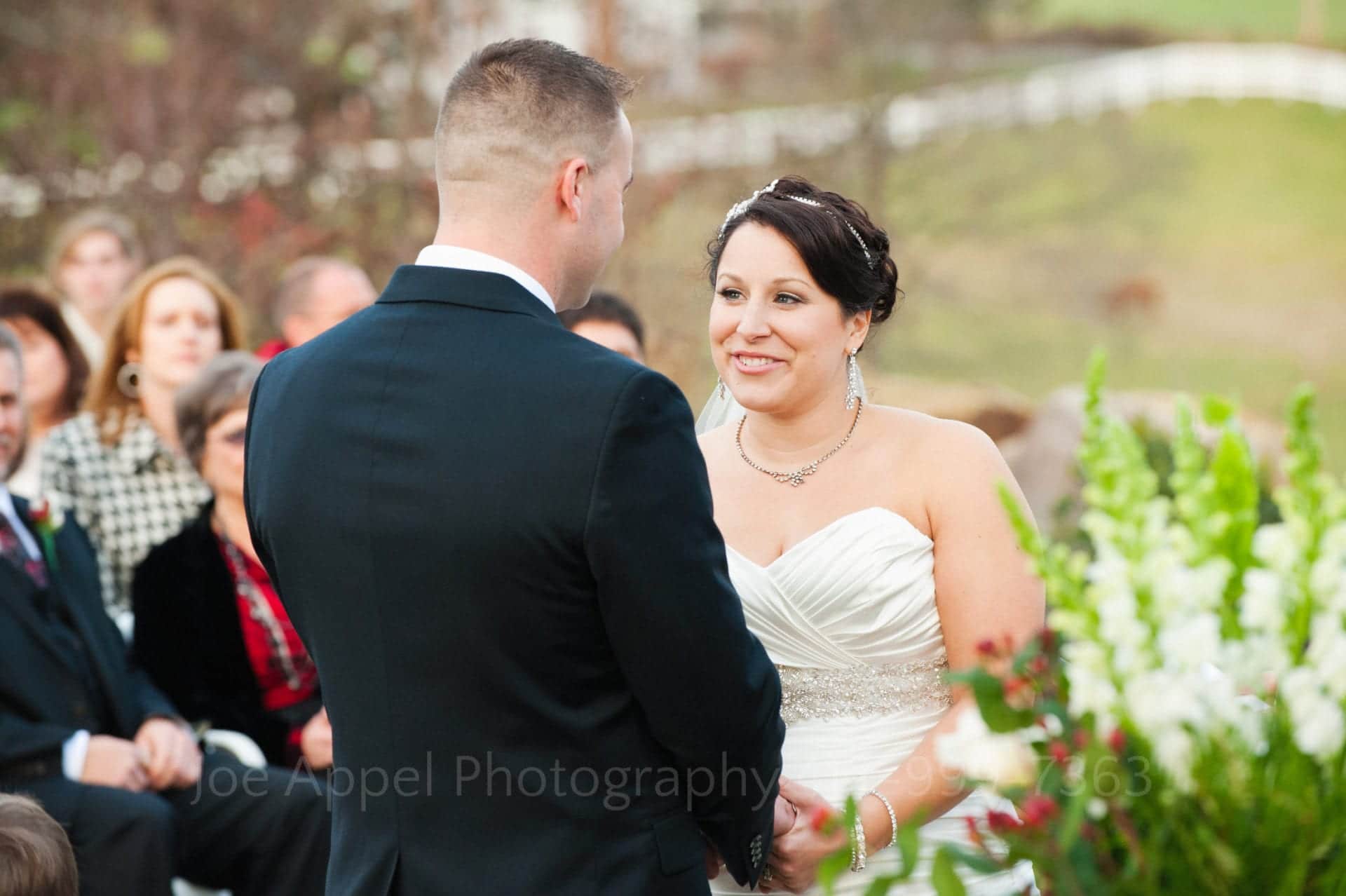 A brown haired bride smiles as she looks up at her groom while exchanging wedding vows. Armstrong Farms Weddings