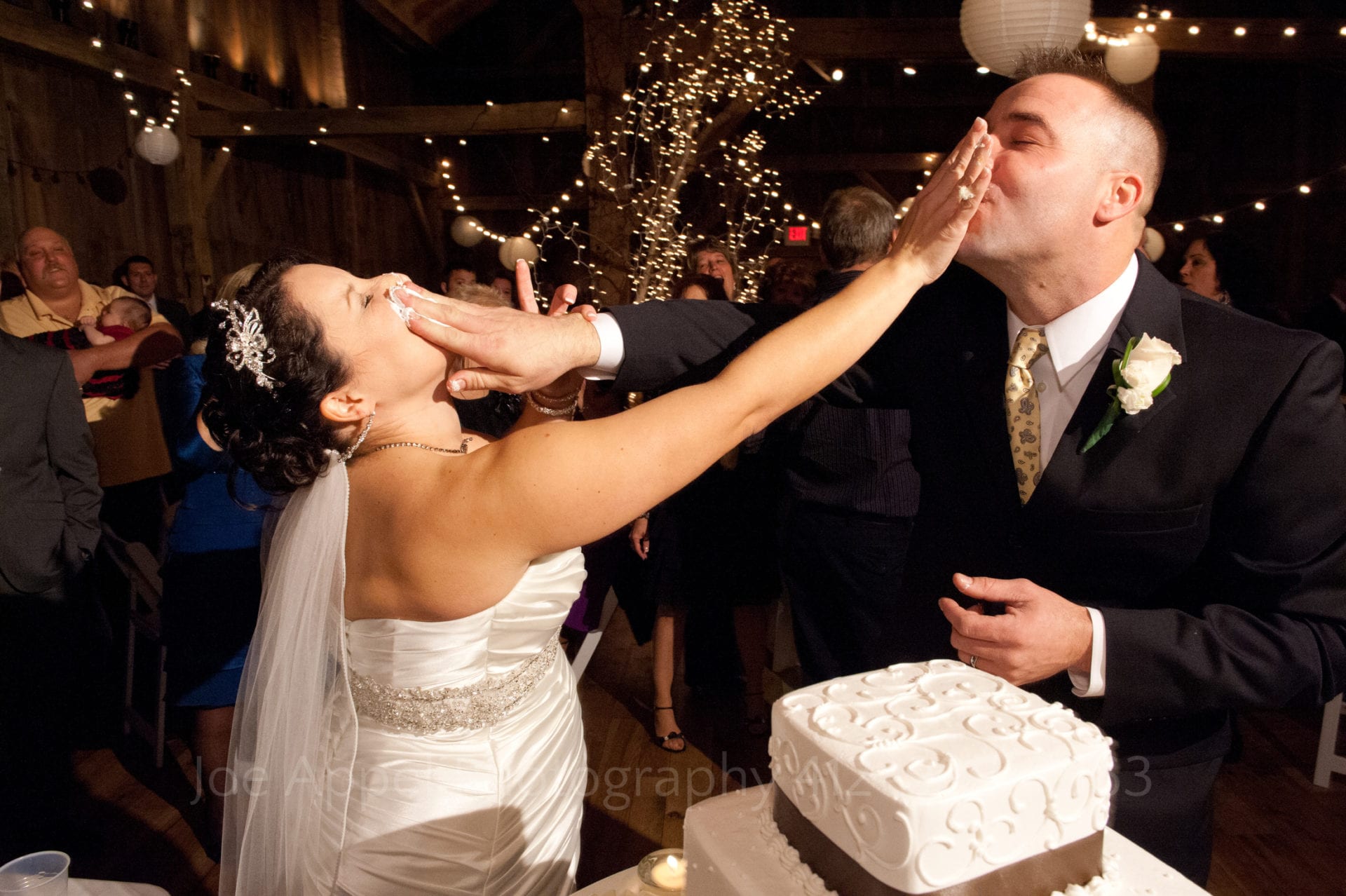 A bride and groom smash wedding cake into each other's faces. Armstrong Farms Weddings
