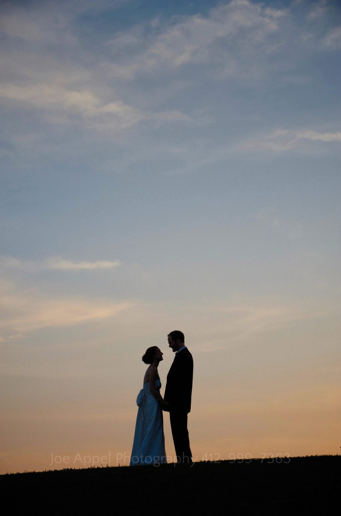 A silhouette of a bride and groom against the sunset at the top of a hill. Armstrong Farms Weddings