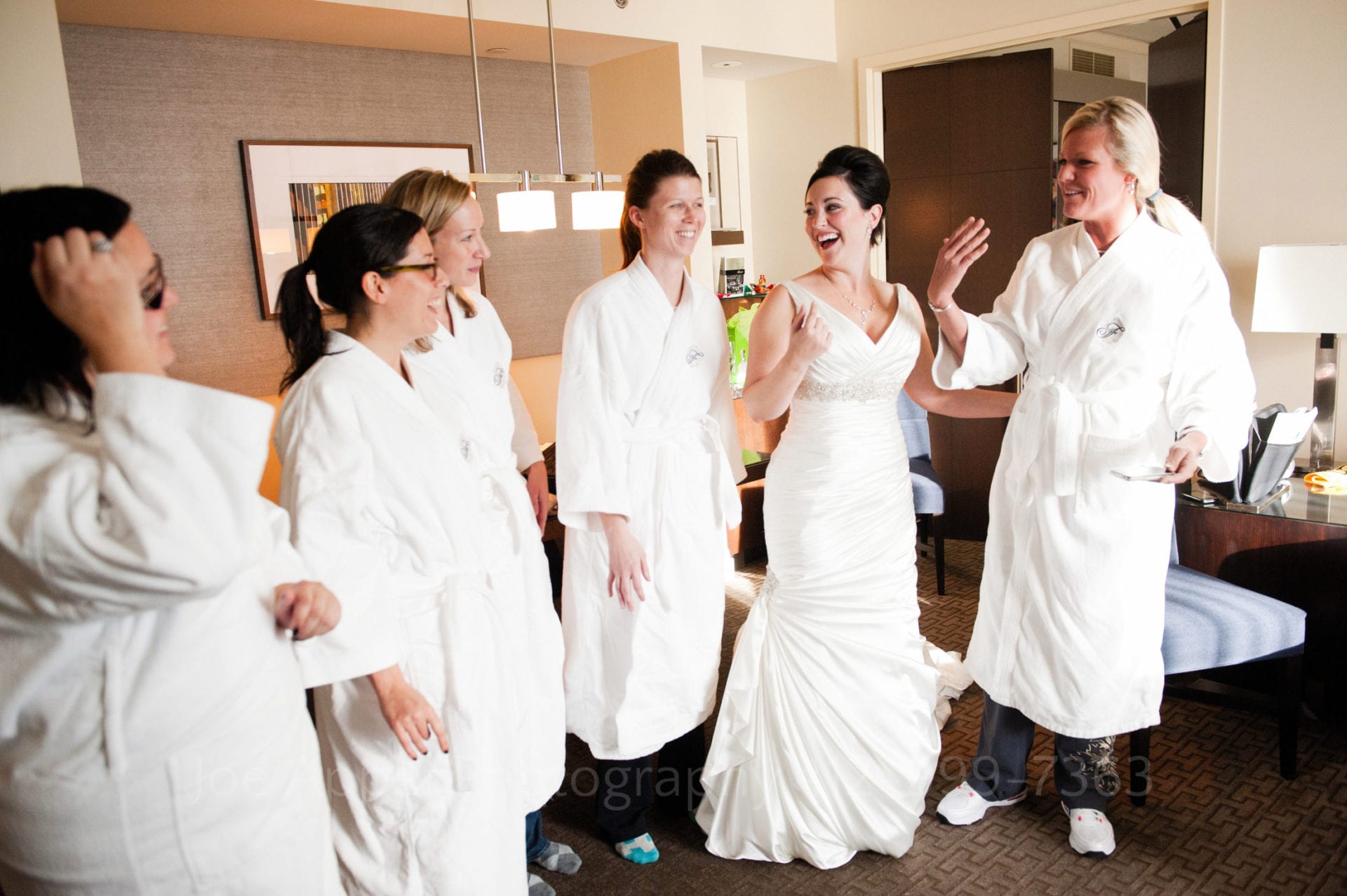 A bride laughs with her bridesmaids who wear white bathrobes Fairmont Hotel Pittsburgh Weddings.