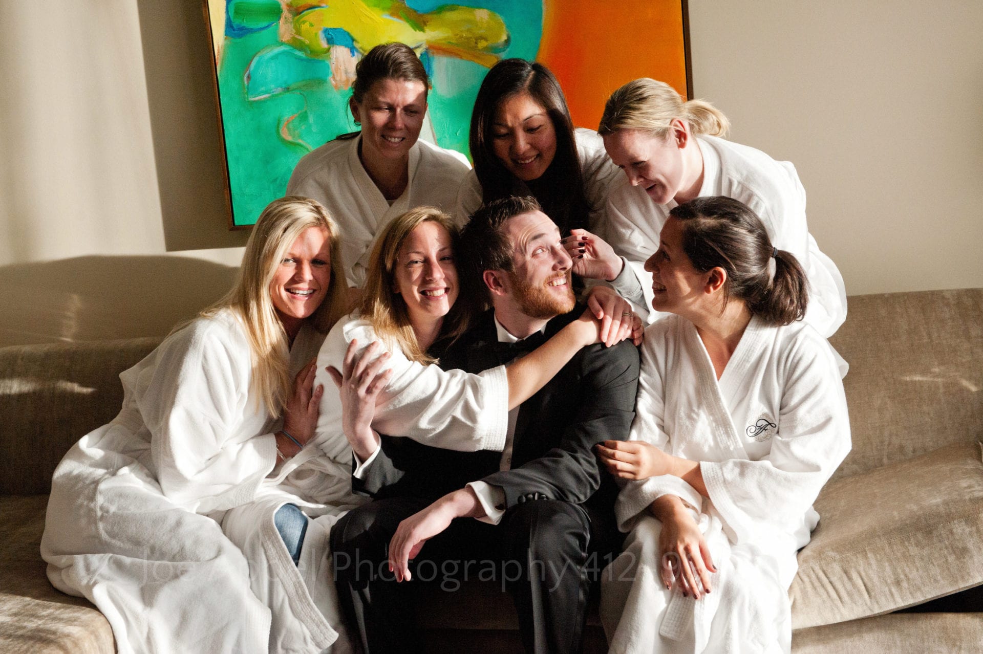 Women in white Fairmont bathrobes surround and embrace a man in a tuxedo Fairmont Hotel Pittsburgh Weddings