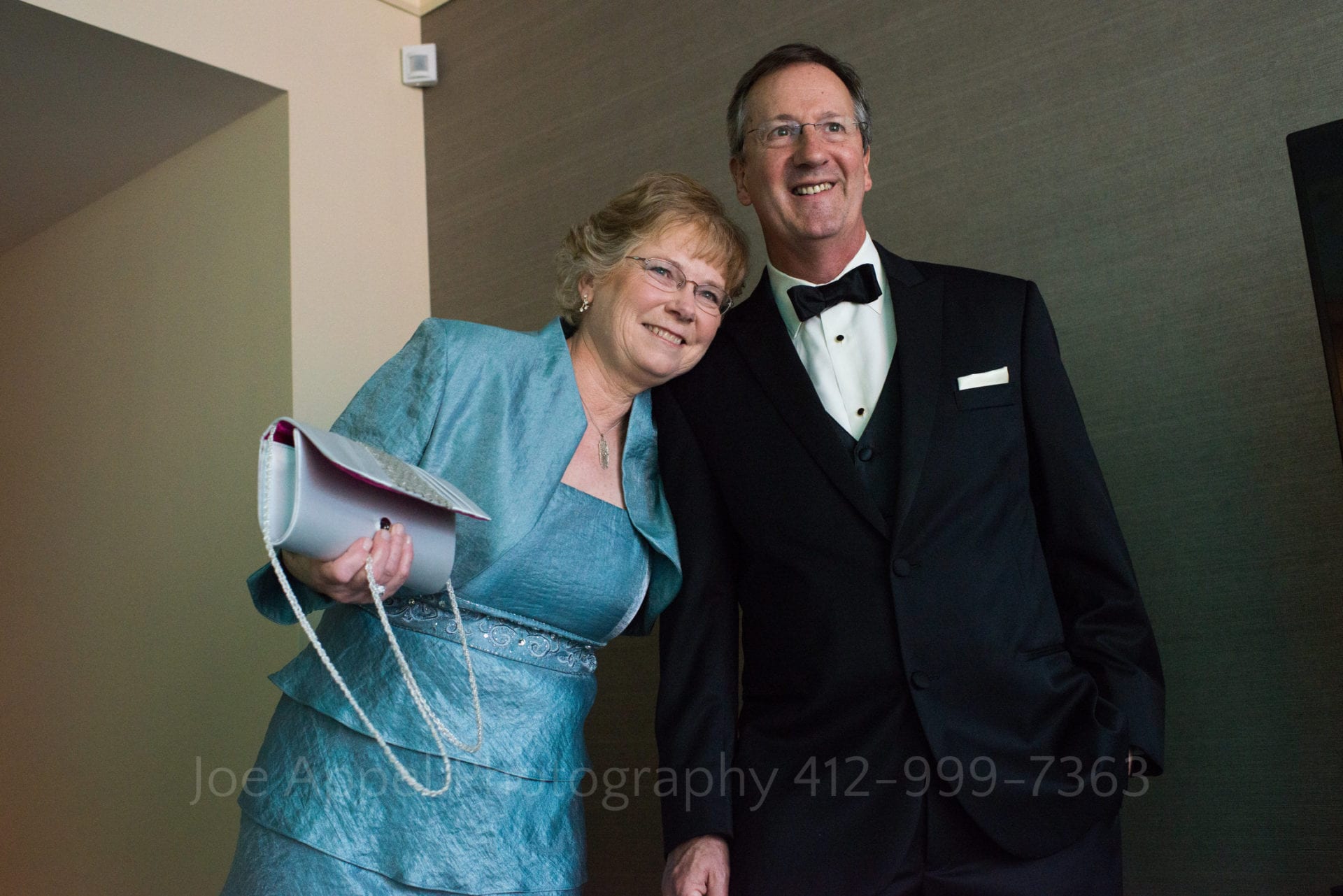 A father and mother smile as they look at their daughter. Father is in a tuxedo and mother a blue dress Fairmont Hotel Pittsburgh Weddings