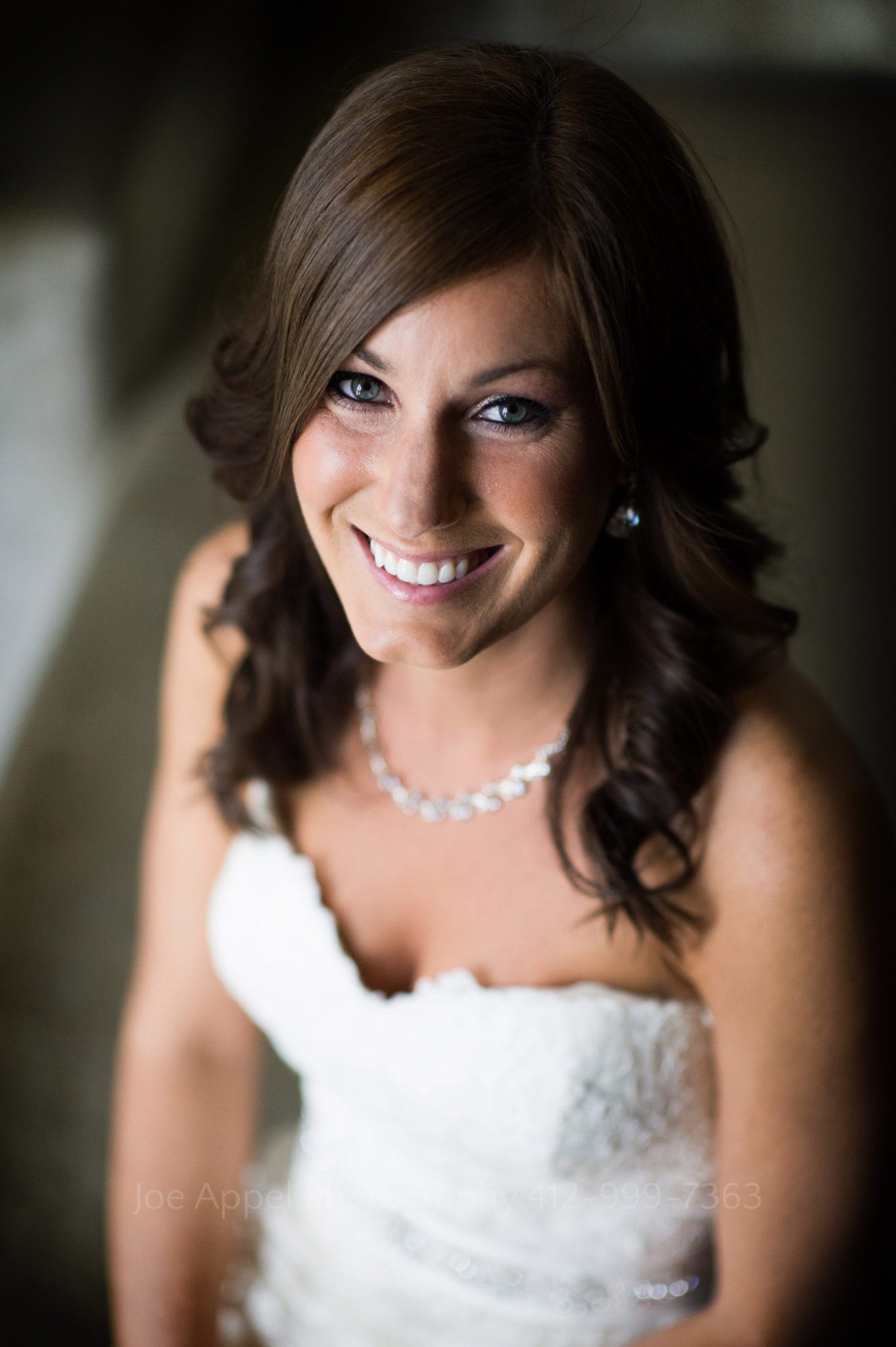 A bride smiles at the camera while wearing a strapless dress and a diamond necklace Fairmont Hotel Pittsburgh Weddings