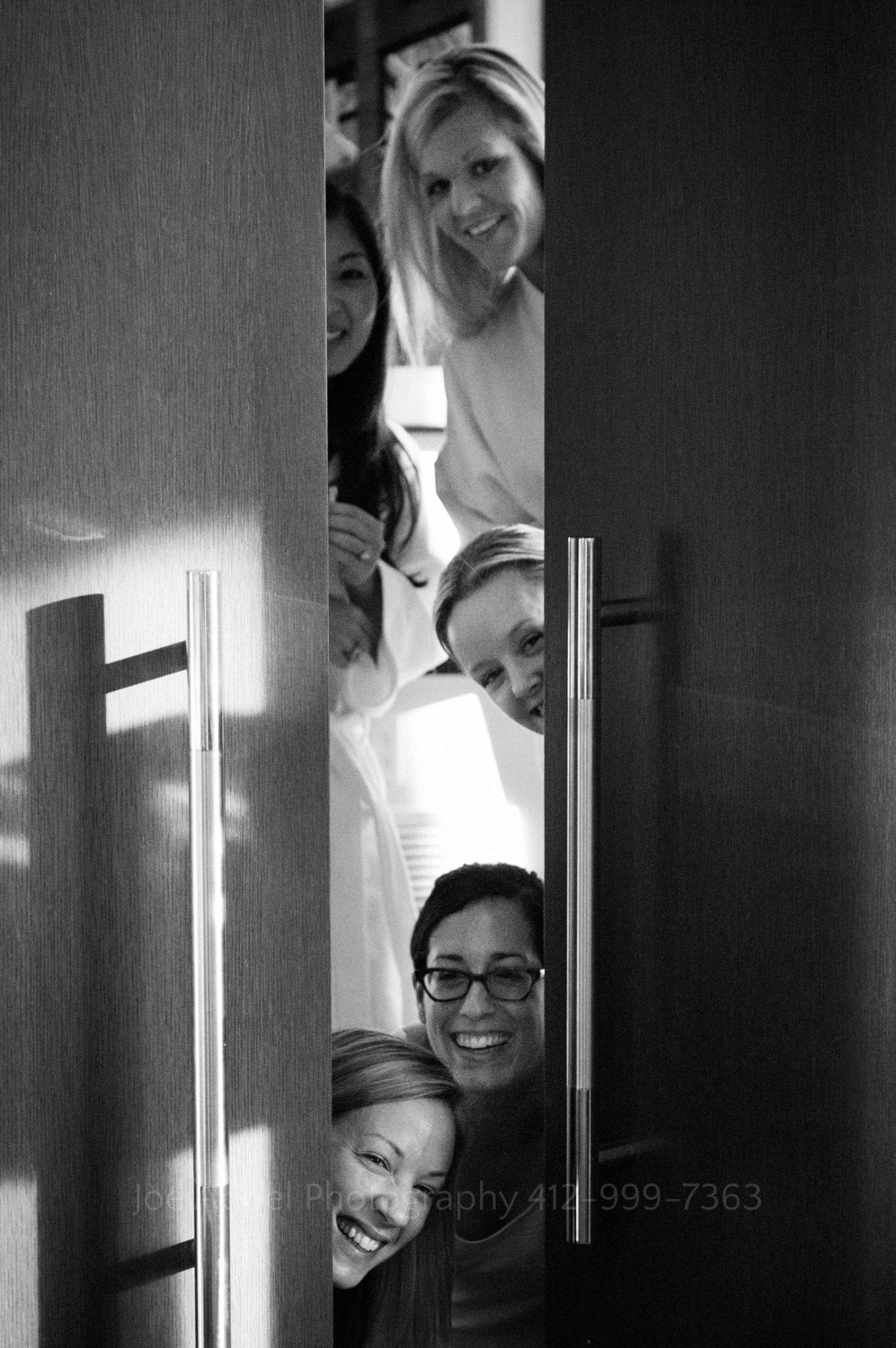 Four women cry as they peek through a partially opened door Fairmont Hotel Pittsburgh Weddings.