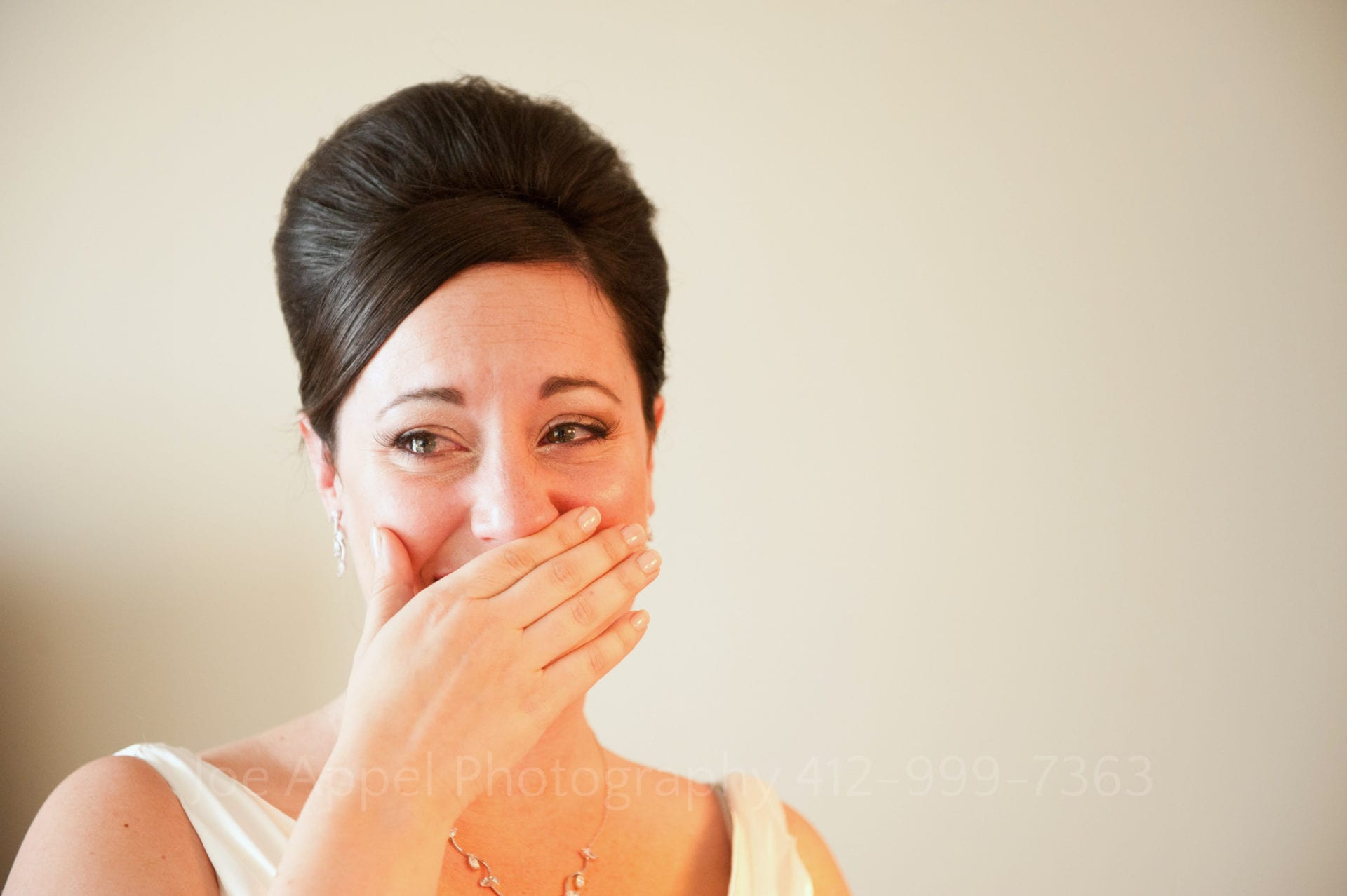 A bride holds her hand in front of her mouth as she tears up Fairmont Hotel Pittsburgh Weddings.
