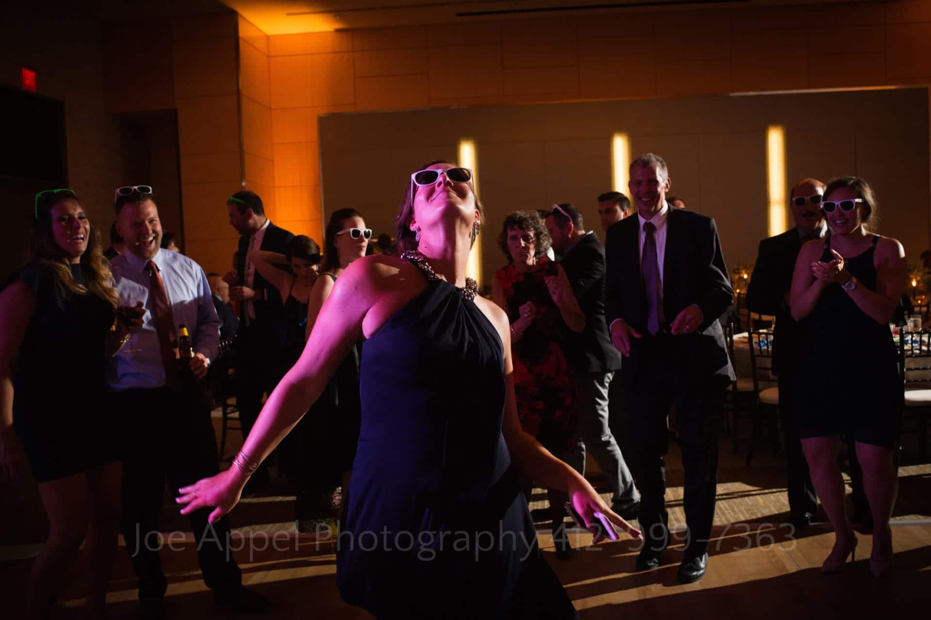 Fairmont Hotel Pittsburgh Weddings A woman wearing sunglasses dances in a purple lit ballroom